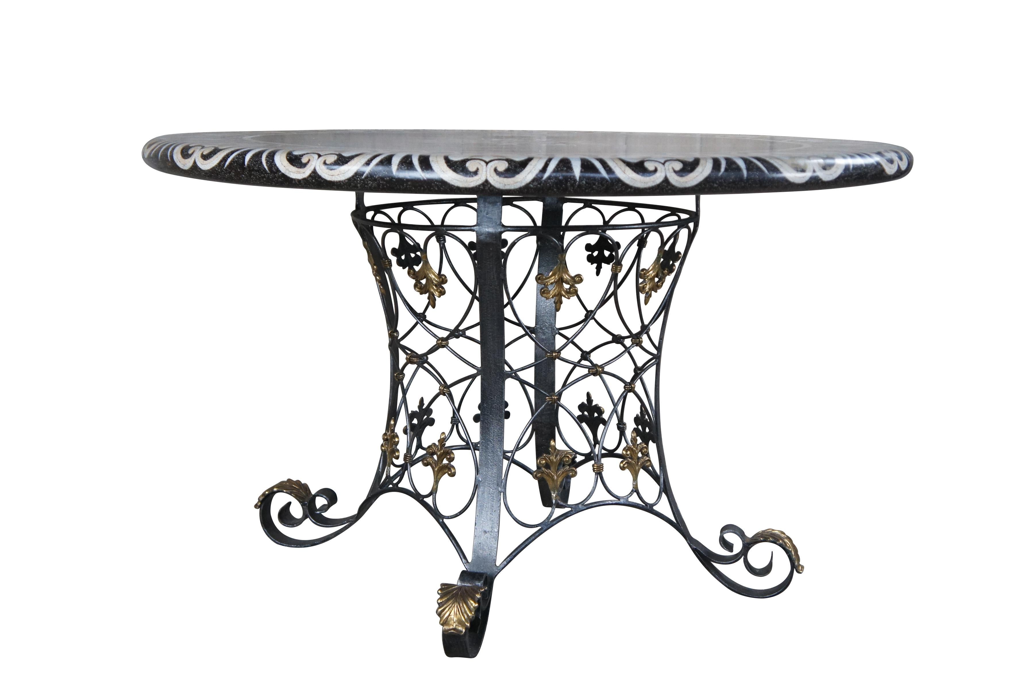 An eye catching handmade Breakfast, Centre or Foyer table by Maitland Smith, circa 1990s. Features a rounded top with inlaid and tessellated stone in the shape of shells and tulips.  The table is supported by an intricate iron base with lattice form