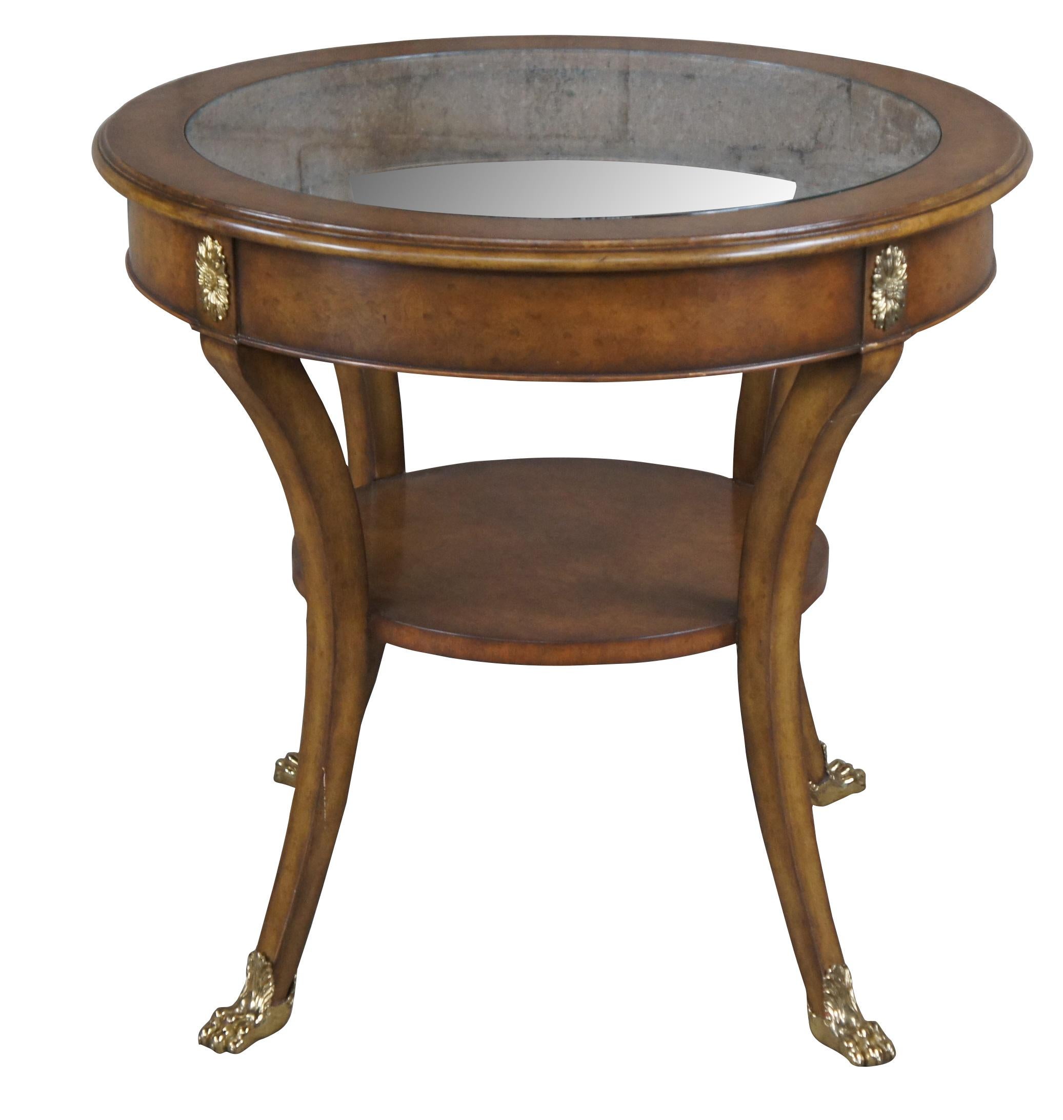 Vintage Maitland Smith gueridon accent table.  Features a round form made of burled walnut feautring glass top, two tiers and downswept legs with brass claw feet.  The apron is accented by brass ormolu medallions.  

Dimensions:
28