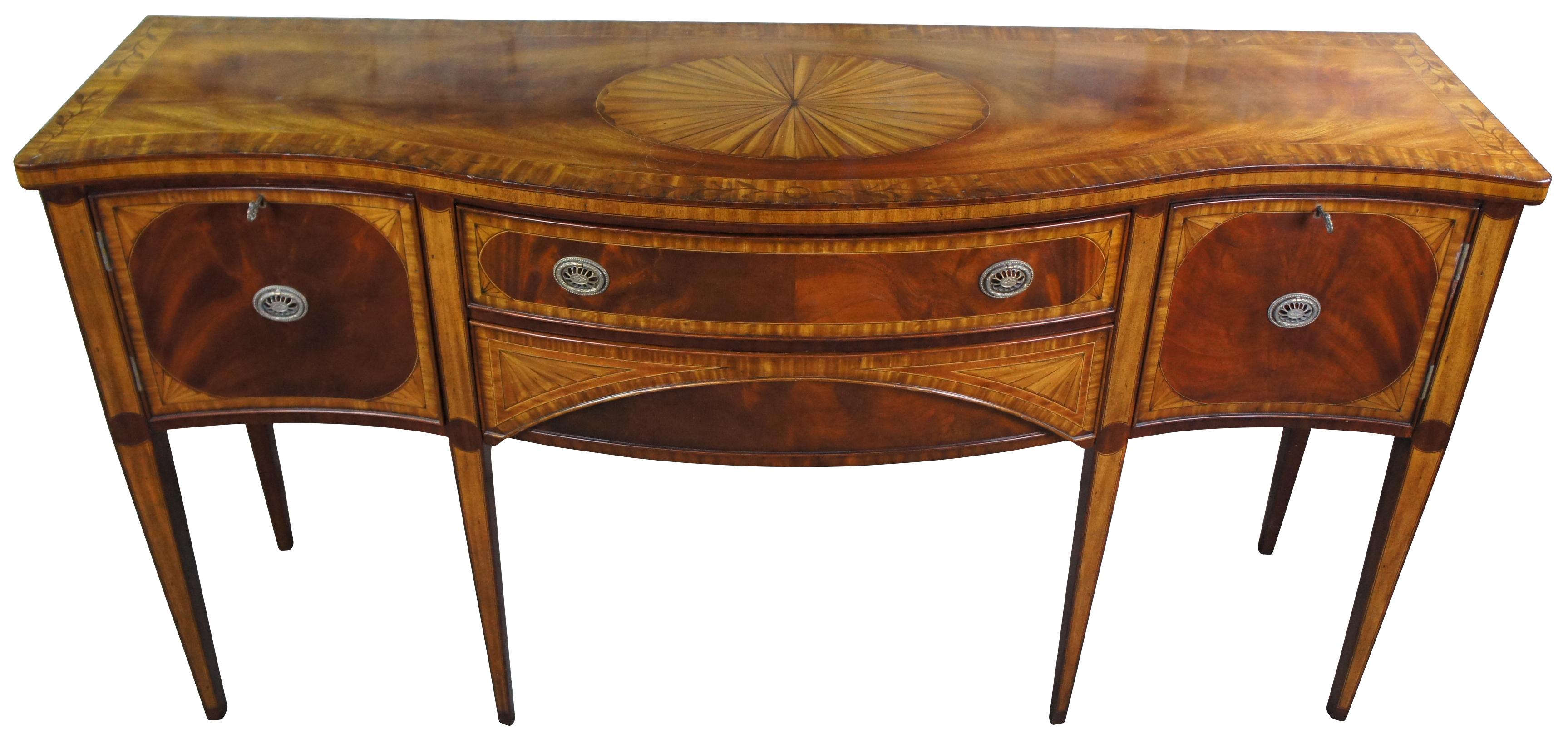 An impressive Hepplewhite or Sheraton inspired sideboard / server. Features a serpentine bowfront form made from mahogany with crotch veener fronts, elegant banding, floral and classic fan inlays. Includes two central drawers flanked by lockable