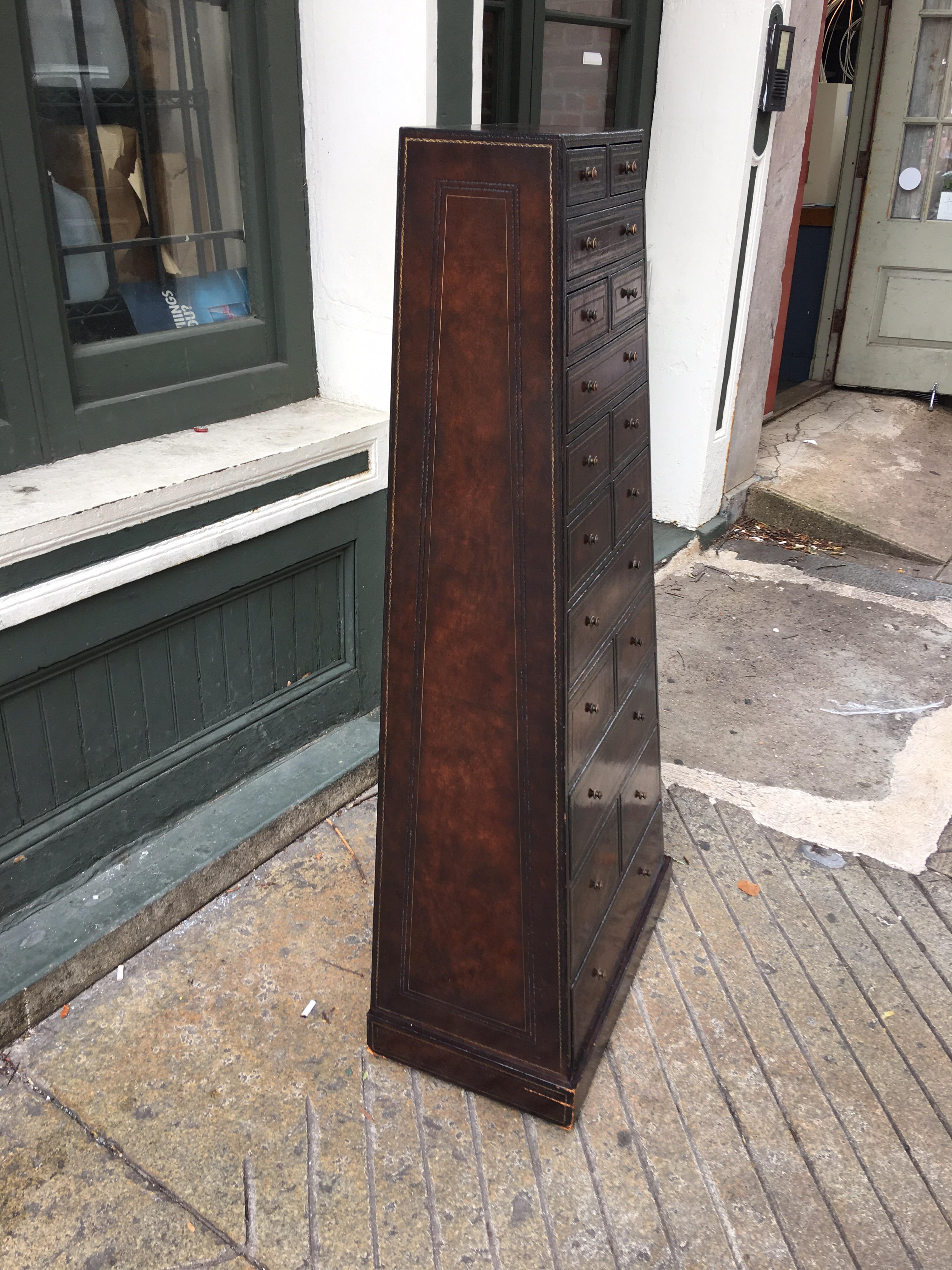 Maitland Smith leather covered tall cabinet. Great to use for a Jewelry collection or Lingerie chest. Every drawer is covered inside and out with paper. Leather has gold embossed designs. 17 drawers that slant from top to bottom both front and sides!