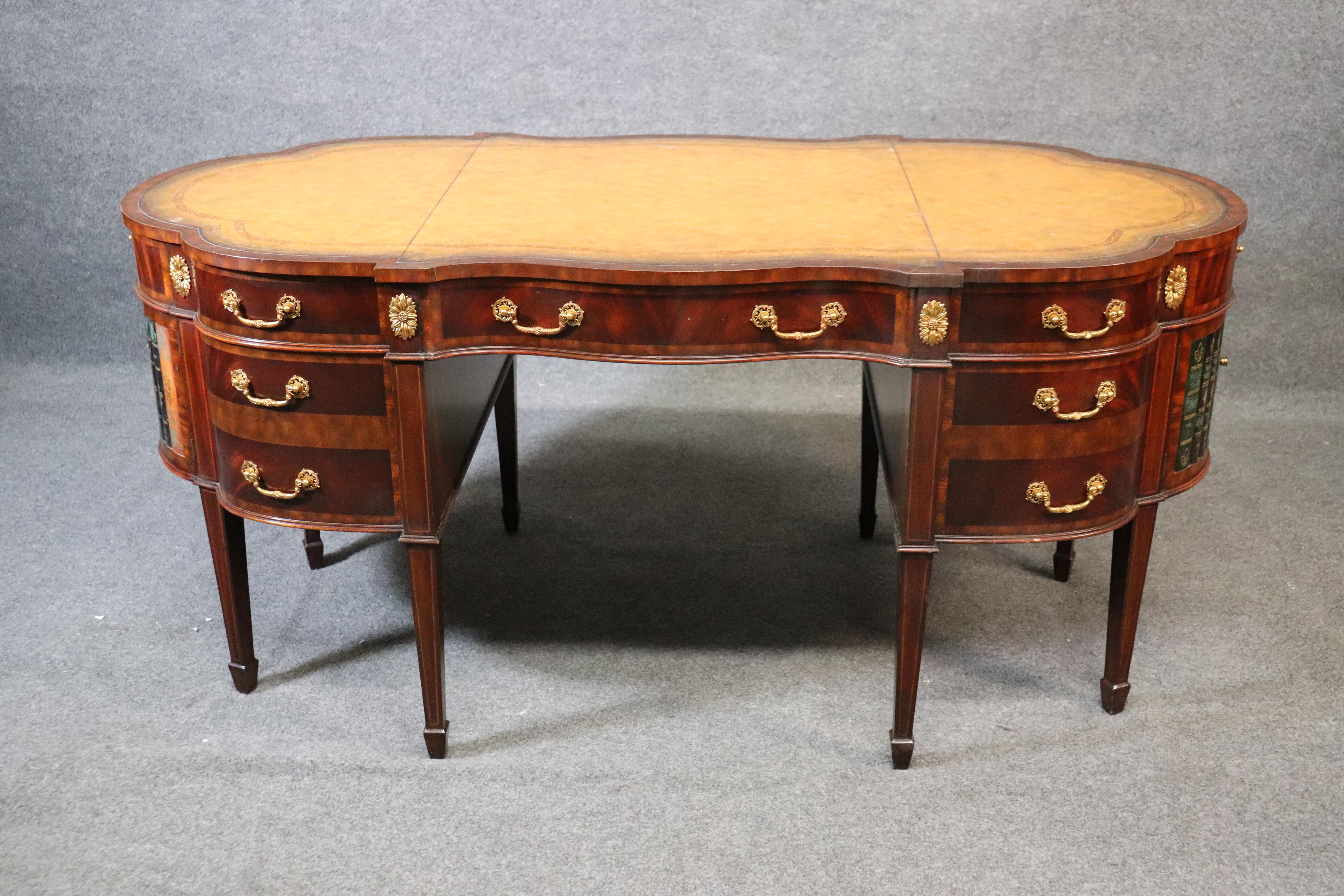 This beautiful Maitland Smith desk features a gorgeous yellow ochre leather top and faux books at each end that conceal an area for actual books or anything else you want to put there. The desk is from the 1990s and is in good vintage condition. The