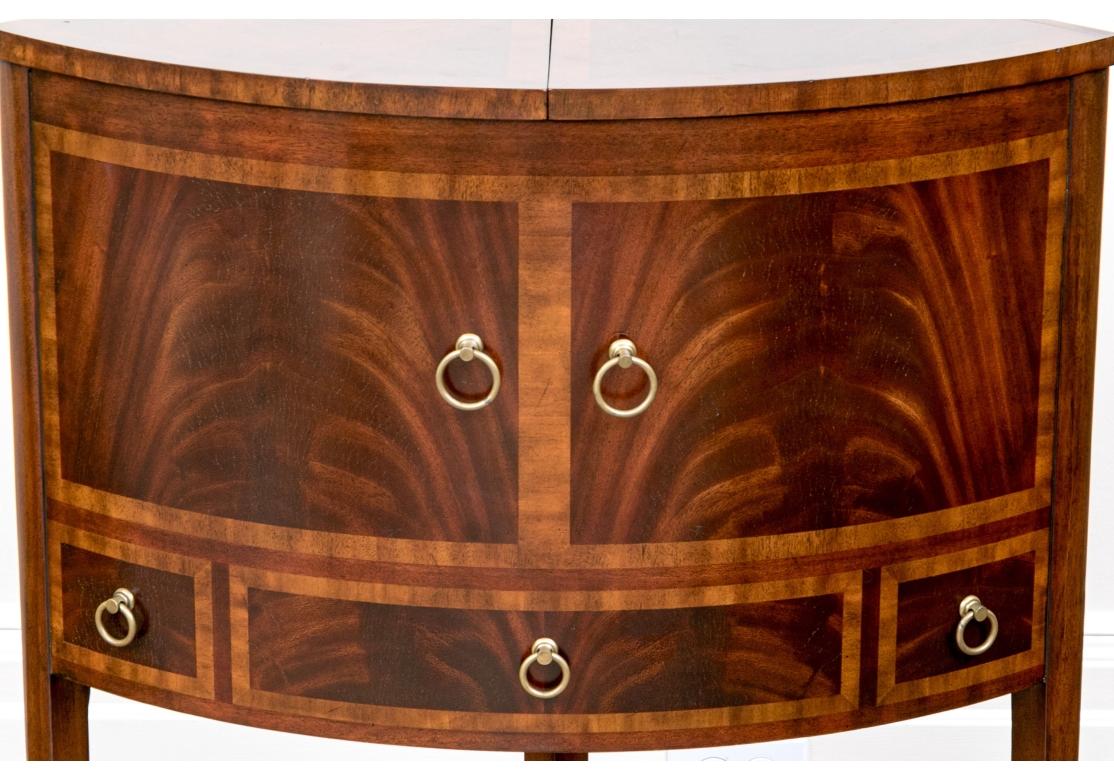 Un beau meuble d'angle Maitland-Smith en acajou richement figuré. Avec un plateau incurvé composé d'une double ouverture à charnière pour révéler le rangement. L'extérieur de la carrosserie présente une fausse porte d'armoire et des tiroirs, avec