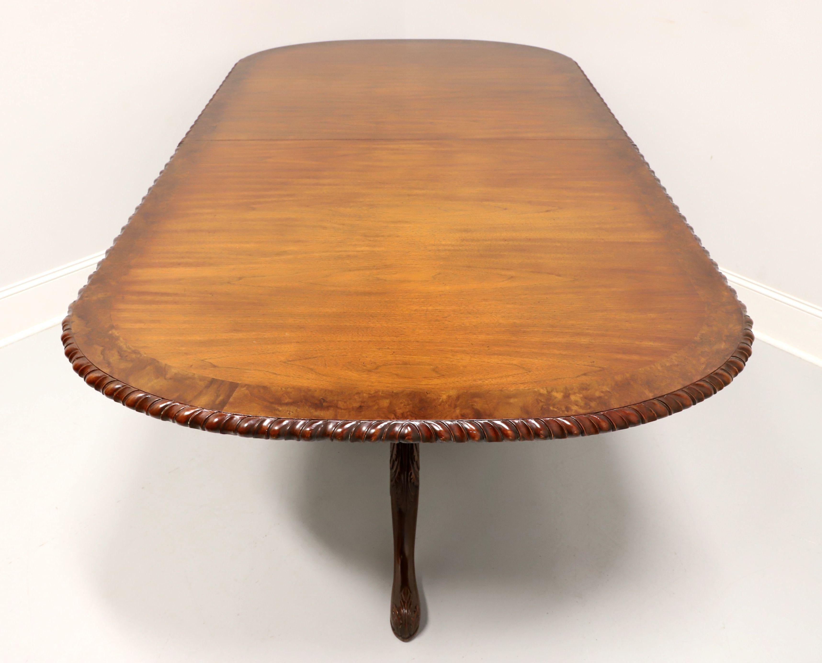 A rectangular double pedestal dining table in the Chippendale style by Maitland Smith. Walnut with burlwood banding to top, gadroon edge, rounded corners, dual decoratively carved pedestals with three legs and carved feet. Includes two extension