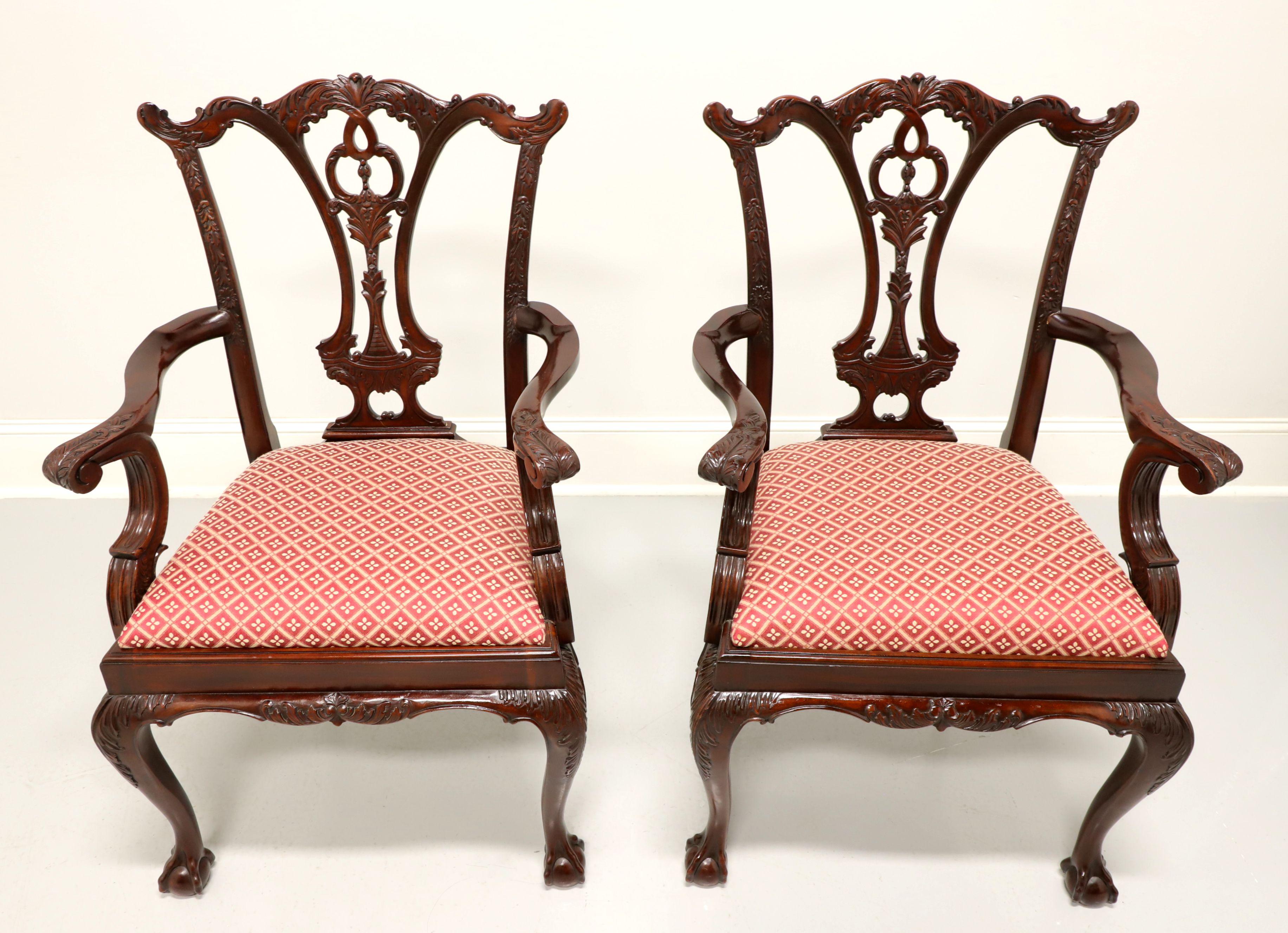 A pair of Chippendale style dining armchairs by Maitland Smith. Solid mahogany with carved crest rails, highly carved back rests, curved arms, red & cream color diamond pattern fabric upholstered seats, carved apron, carved acanthus leaf to knees,