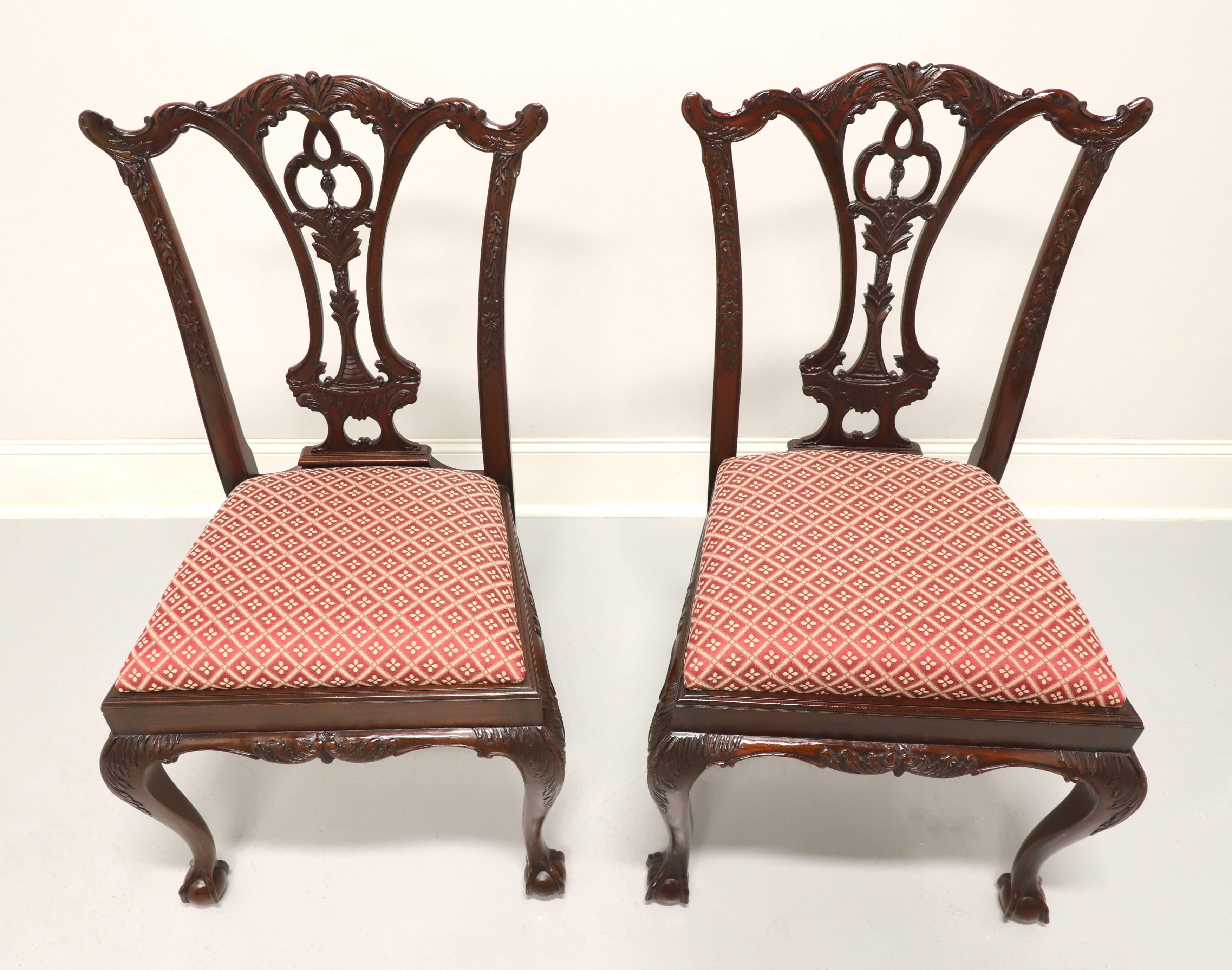 A pair of Chippendale style dining side chairs by Maitland Smith. Solid mahogany with carved crest rails, highly carved back rests, red & cream color diamond pattern fabric upholstered seats, carved apron, carved acanthus leaf to knees, curved legs