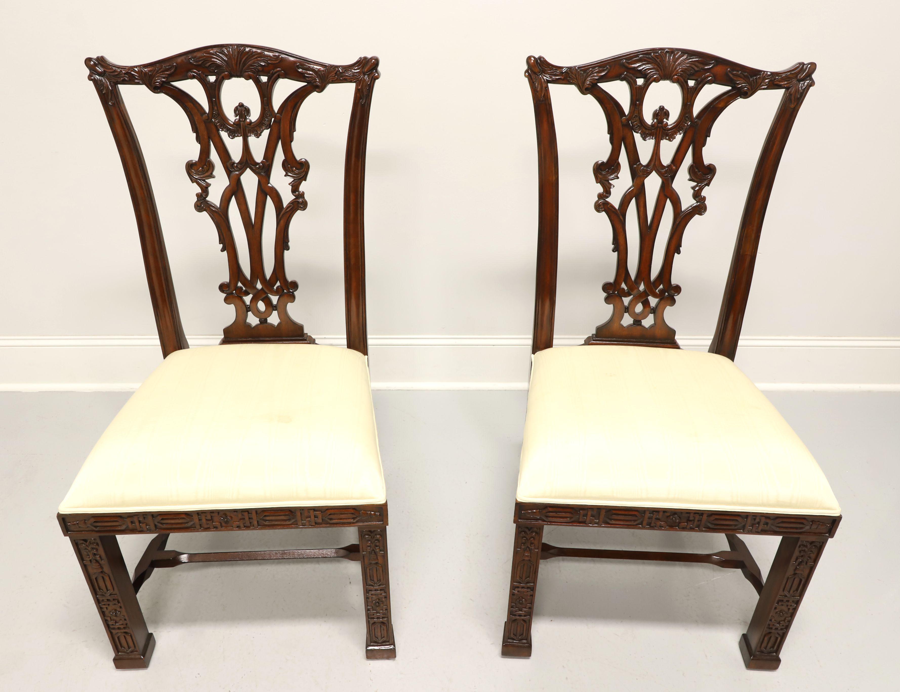 A pair of Chippendale style dining side chairs by Maitland Smith. Solid mahogany with carved crest rail, backrest, decorative fretwork details to apron & straight front legs, and stretchers. Seats are upholstered in a neutral cream colored fabric.