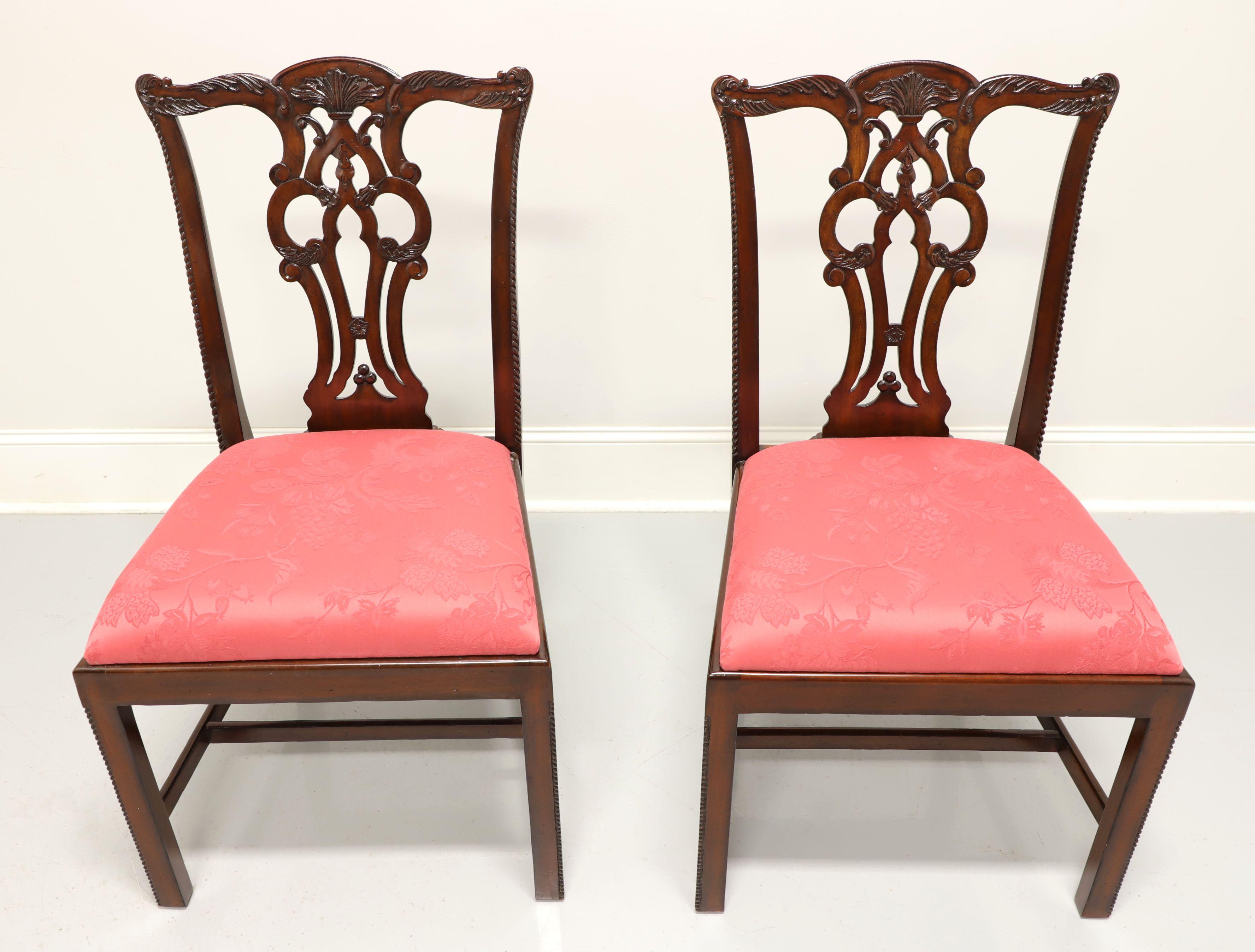 A pair of Chippendale style dining side chairs by Maitland Smith. Solid mahogany with carved crest rail, backsplat, straight legs with decorative beading and stretchers. Seats upholstered in a rose colored brocade like fabric. Made in Indonesia, in