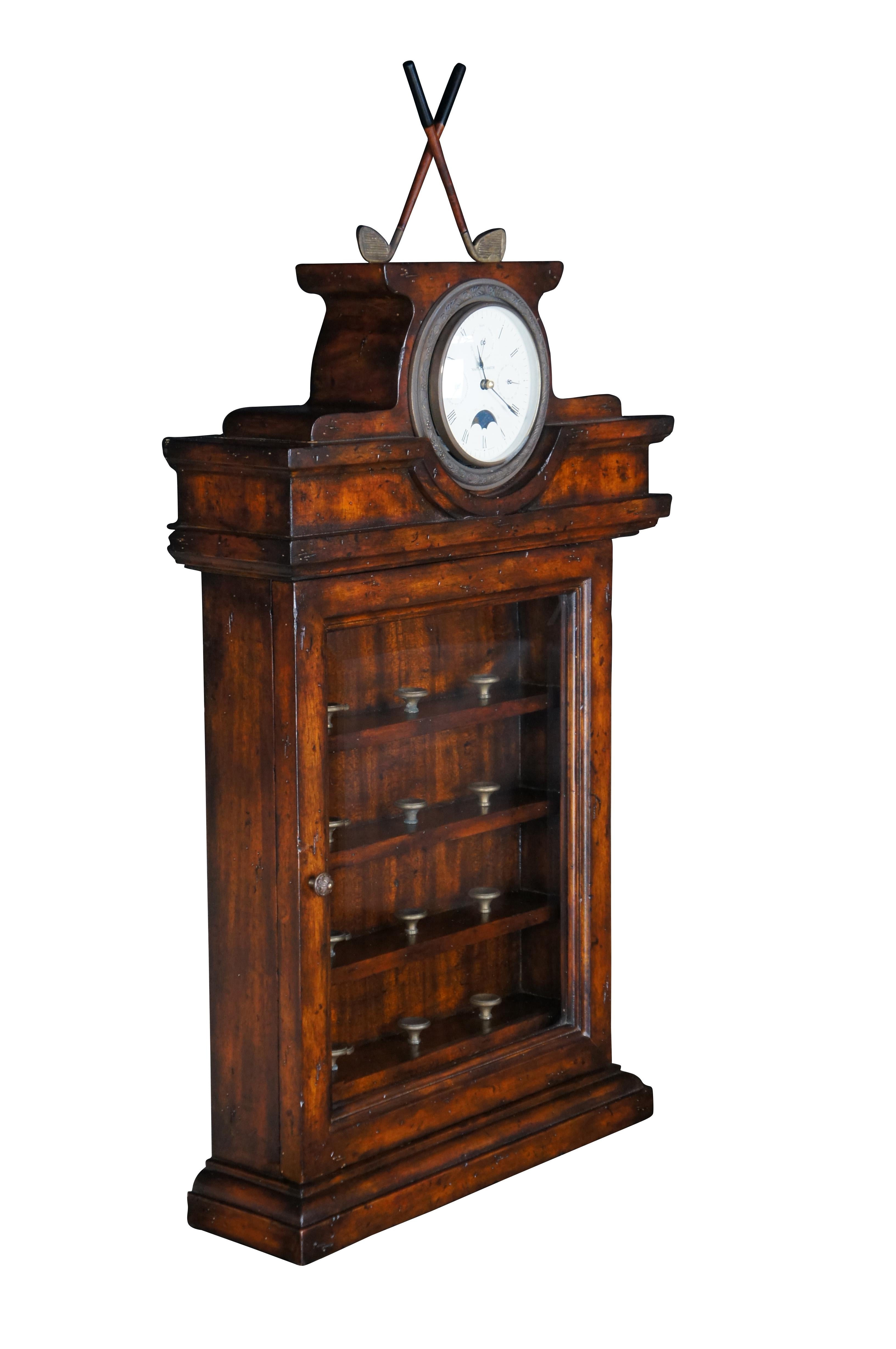 Raro mueble curio de Maitland Smith. De caoba naturalmente desgastada, con frontal de cristal que se abre a cuatro estantes con pedestales de latón en forma de tee destinados a exponer pelotas de golf. La corona del reloj muestra unos palos de golf