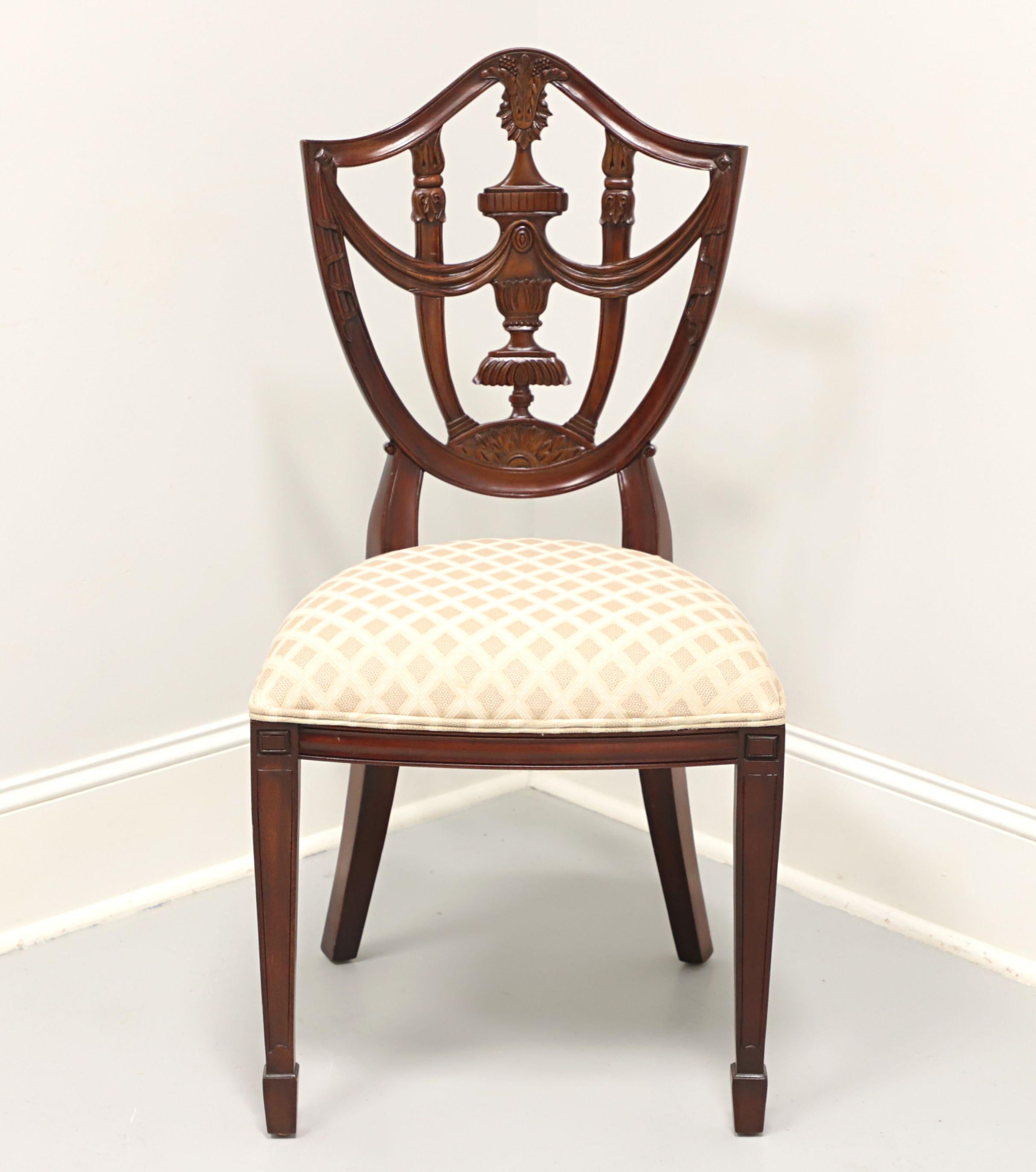 A Hepplewhite style dining side chair by Maitland Smith. Mahogany with decoratively carved back, cream & gold color patterned fabric upholstered seat, straight legs and spade feet. Made in Indonesia, in the late 20th century.

Measures: Overall:
