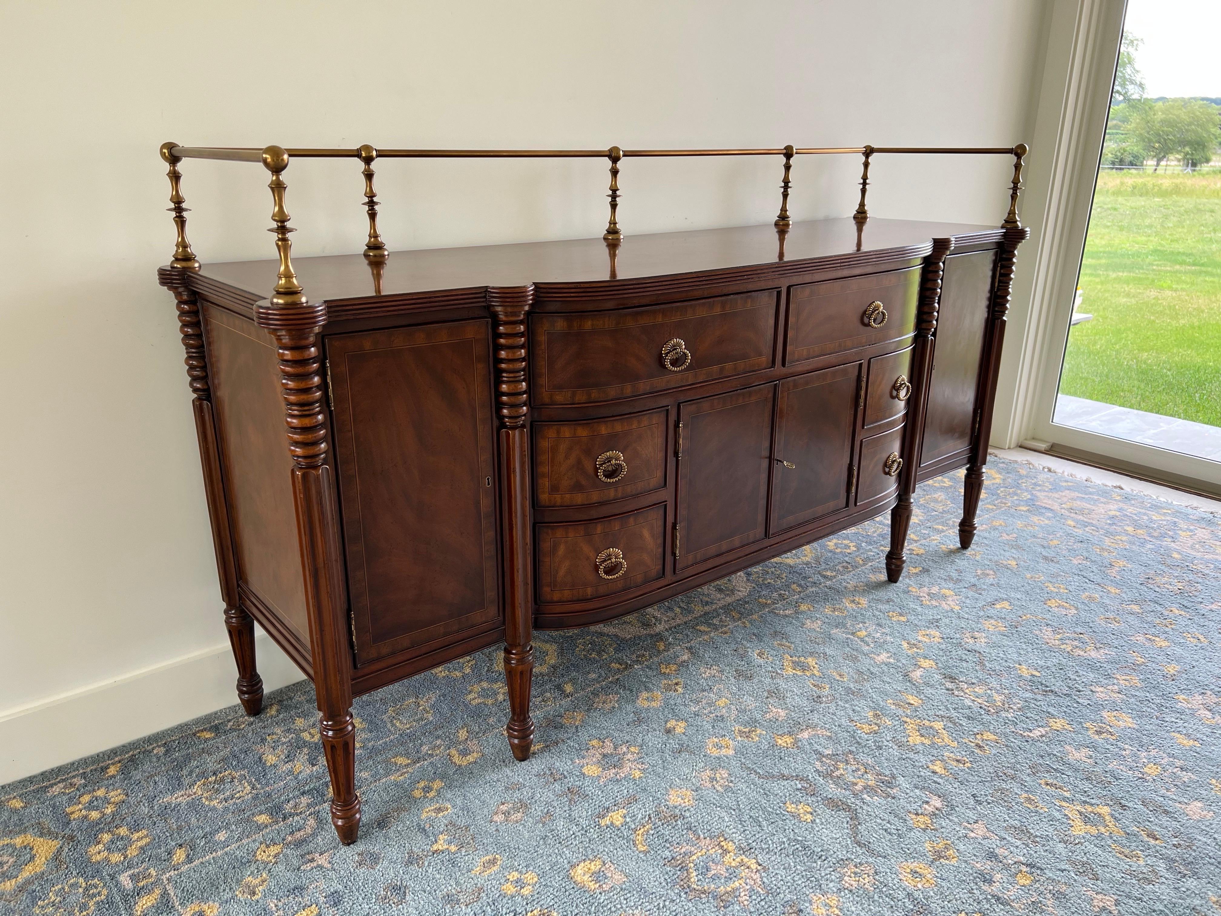 Maitland-Smith Mahogany Sideboard with Brass Gallery Rail.
The sideboard crafted by Maitland-Smith exhibits a refined mahogany construction, characterized by its rich, deep hue and polished finish. The design incorporates a distinctive brass gallery