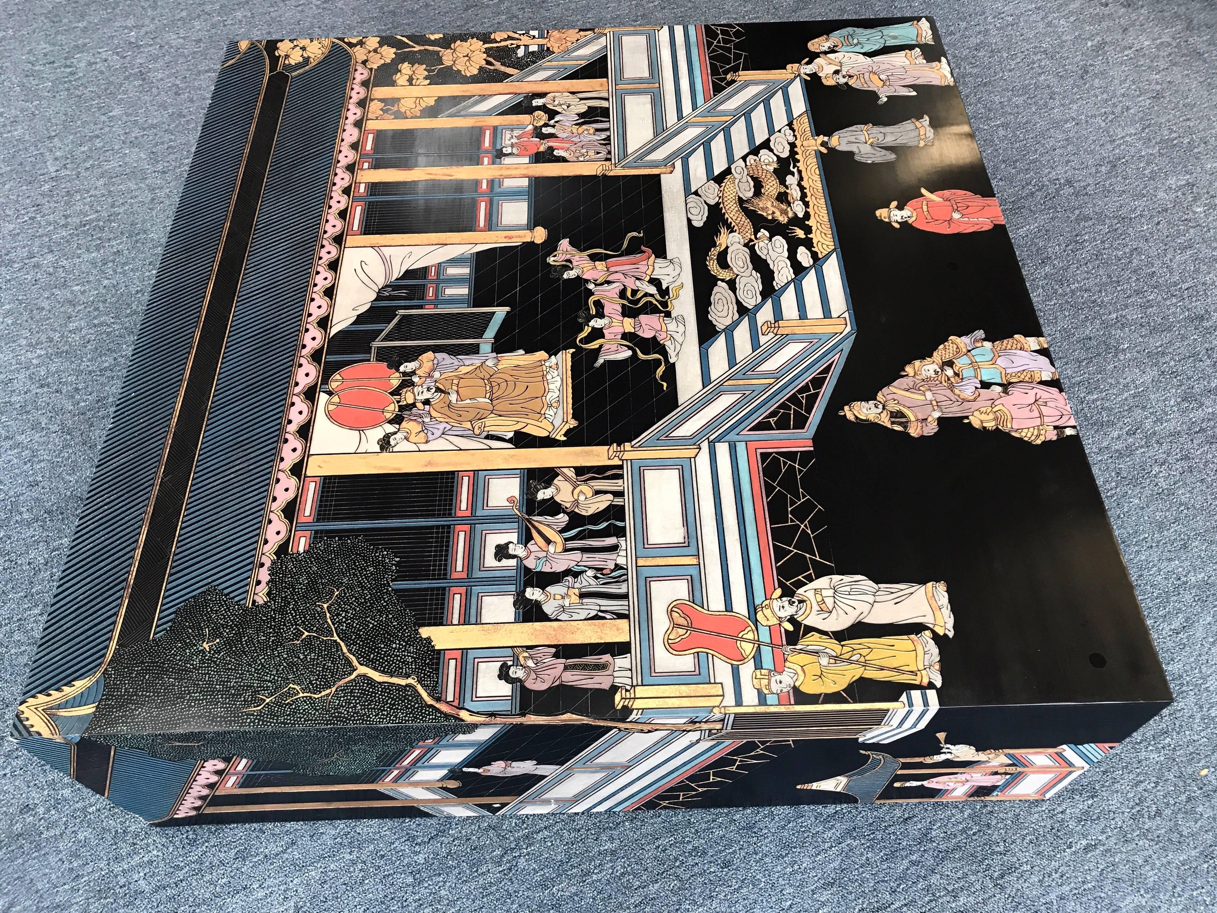 Exquisite black lacquer Maitland Smith oversized 50 x 50 inch table is carved and hand-painted and topped with glass for protection. It's decorative visual elements of a Chinese village scene reach down both sides in vibrant colors. Comes with a