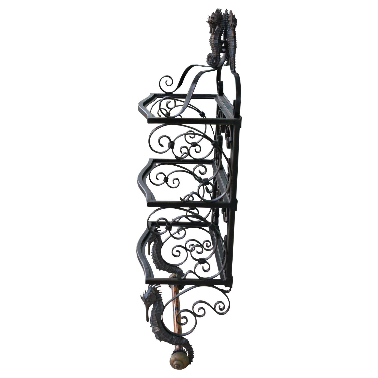 Gorgeous display shelf by Maitland Smith made from wrought iron featuring a nautical theme with seahorses and shells, donning a bamboo dowel on the bottom.