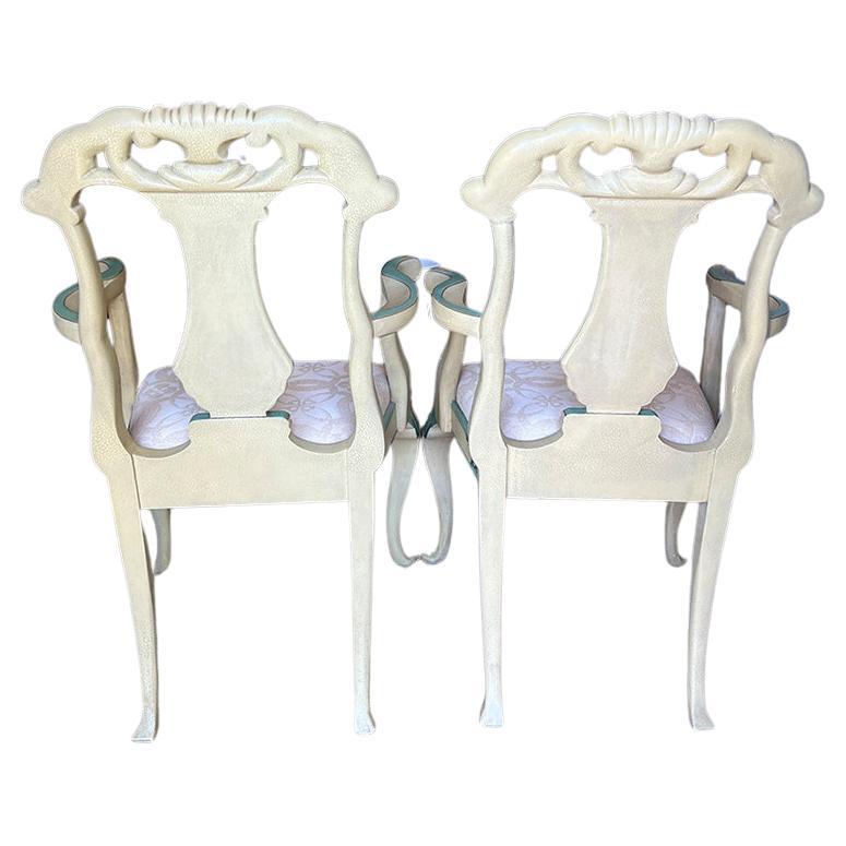 An exquisite pair of hand-painted grotto armchairs by Maitland Smith. This pair will be an excellent addition to any space. The pair are hand carved and feature a pink and green shell motif on the back. The chairs are painted in a creamy white