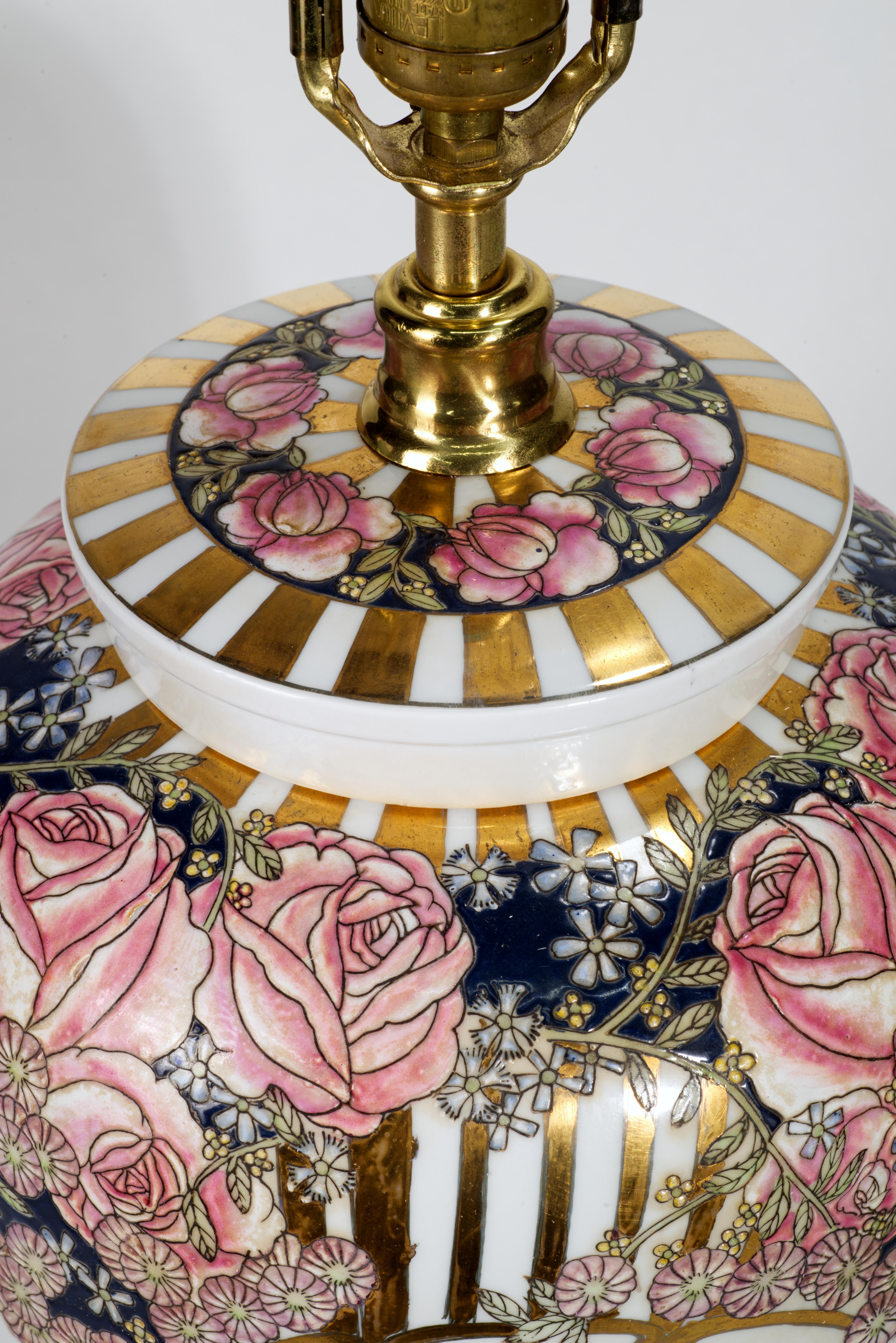 Vintage Maitland Smith hand crafted porcelain ginger jar table lamp features striking, unusual decor with English chintz roses and other florals reinterpreted in traditional Chinoiserie style in pink, white, black, and gold colors and set off