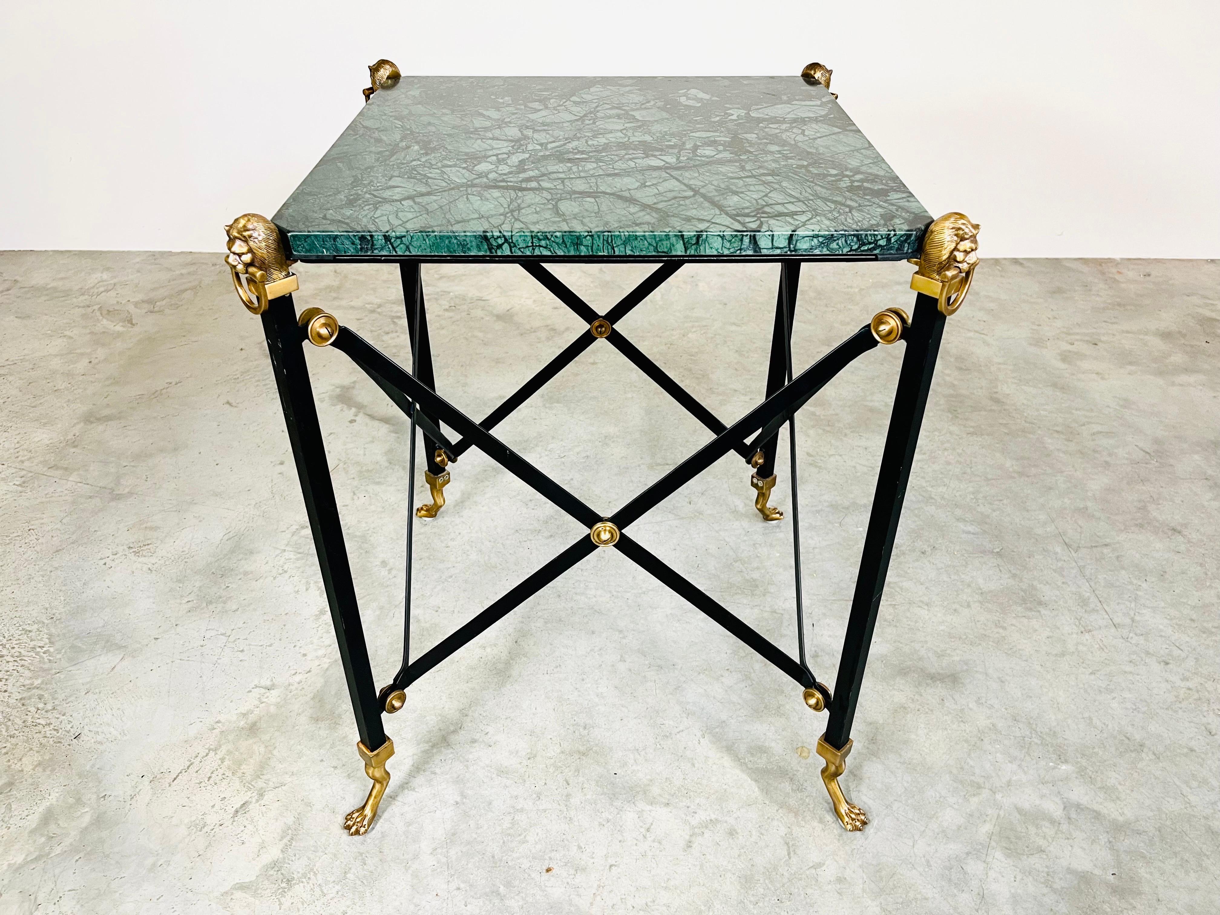 A verdigris marble top occasional table having a black iron Campaign style base with X stretchers and legs topped with brass lion heads and footed with lion paws. A stunning table that demands the eye. Maitland Smith, circa 1980. Outstanding overall