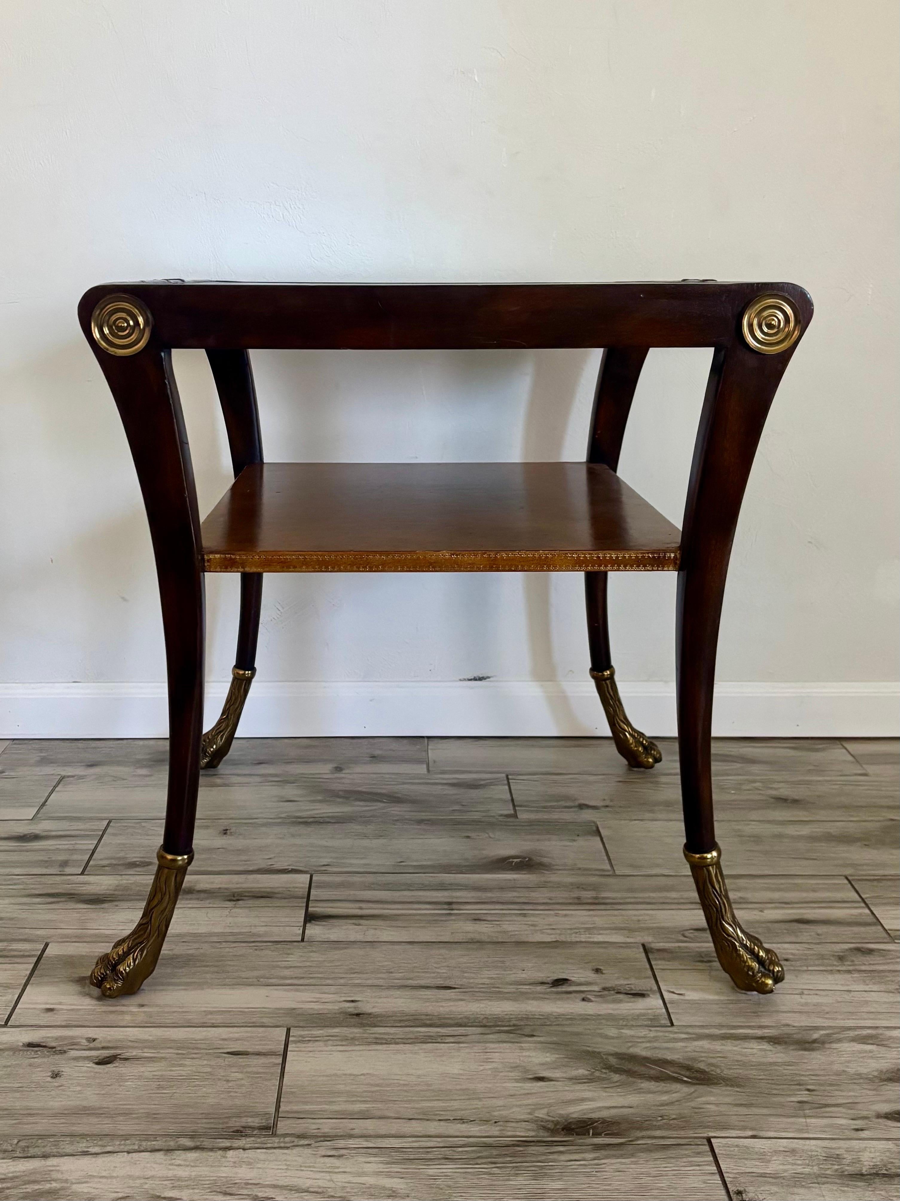 Regency style side table made by Maitland Smith. Excellent craftsmanship and a collection of excellent materials. Wooden Klismos style frame with brass feet and medallions. Two table tops covered in leather. 
