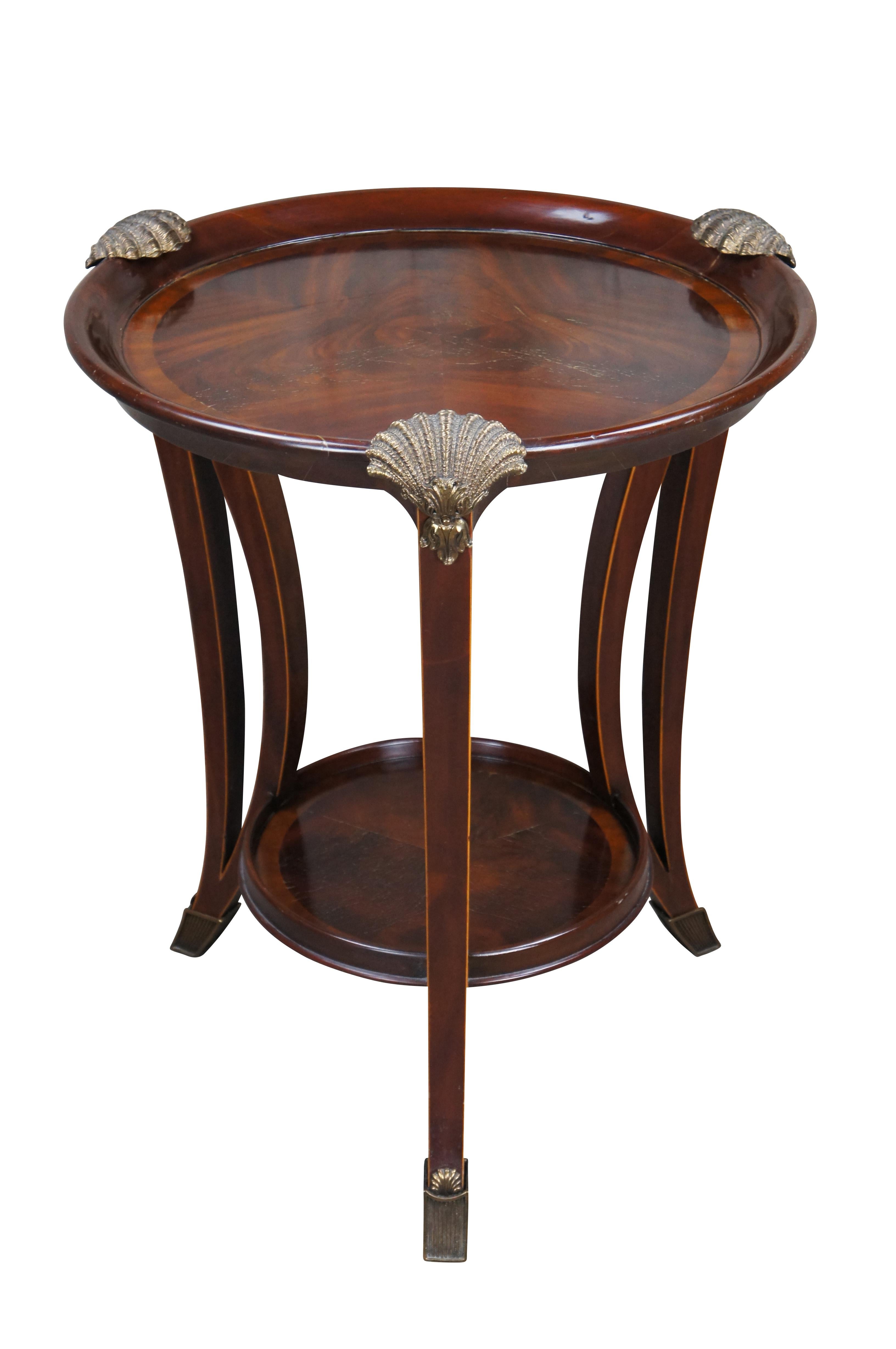 An impressive late 20th century two tier side table / sculpture stand by Maitland Smith. Features a round form inset top over three downswept and pierced square form legs leading to brass capped feet. The top showcases scalloped bronze ormolu mounts