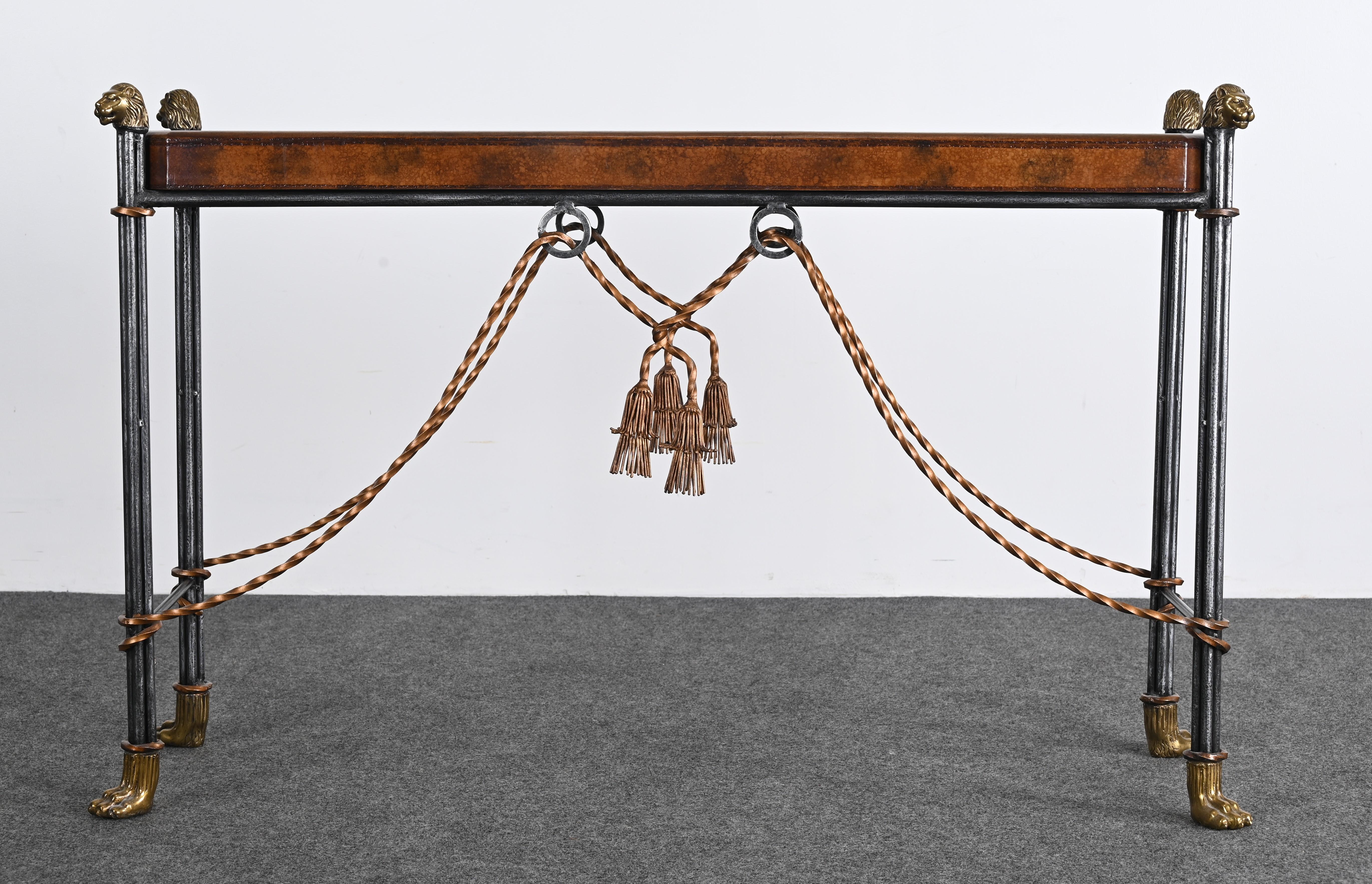 A Maitland Smith-style Leather Top Lion Head Console, 1990s. This handsome steel and brass console table is beautifully accented with a leather-embossed top. The detail of the tassels, the claw feet, and lion heads is spectacular. The scale and size