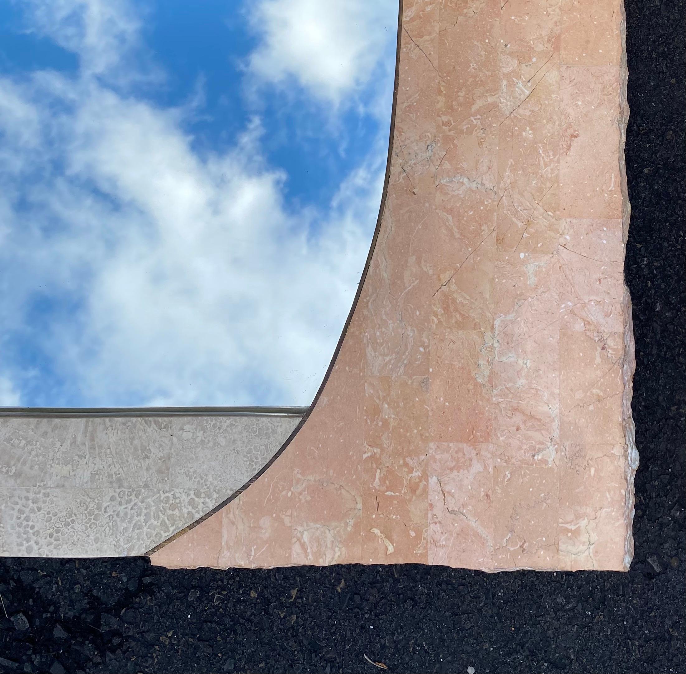 Pair of large modern tessellated pink-coral marble and travertine fossil stone wall mirrors by Magnussen Presidential Furniture Company. These sculptural organic mosaic mirrors feature a freeform raw edge draped design with brass inlay trim. Perfect