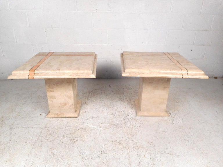 Stylish pair of end tables in the style of Maitland Smith. Sleek pedestal bases and a striking tessellated faux-marble construction. This pair is sure to make an impression in any modern interior, circa 1980s. Please confirm item location with
