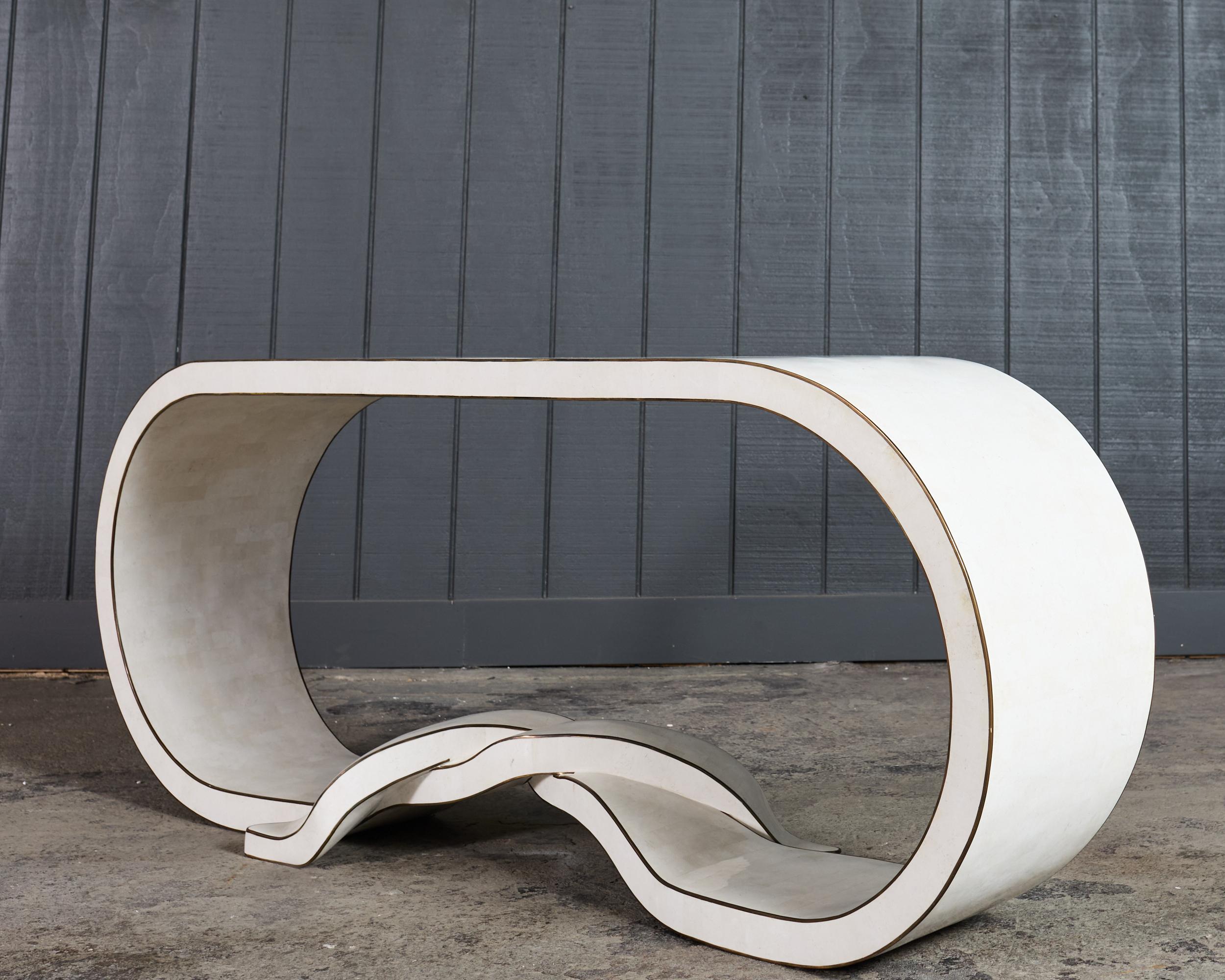 Consola elegante y graciosa elaborada con una chapa de piedra teselada en forma de anillo infinito alargado con extremos de cinta doblados. El diseño postmoderno tiene una presencia y un perfil audaces que añaden una puntuación arquitectónica a los