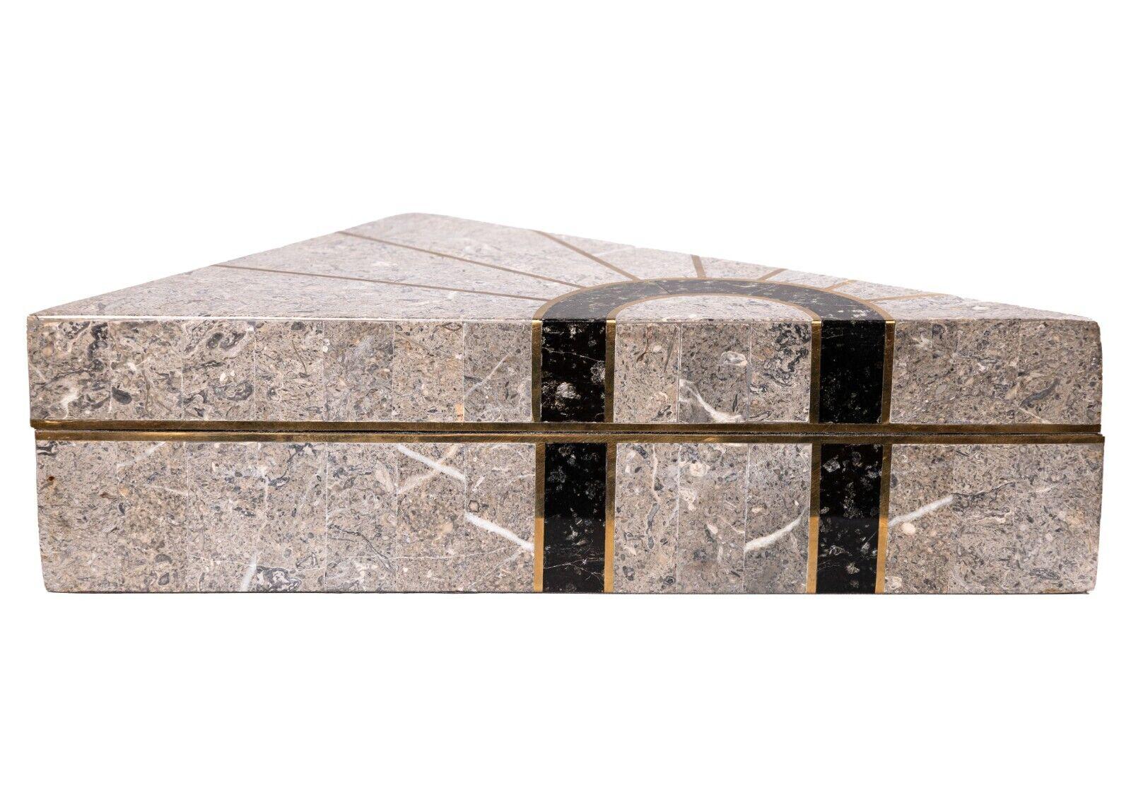 A Maitland Smith tessellated stone triangle box. A gorgeous décor box from designers Maitland Smith. This small box is constructed with a series of beautiful tessellated stone tiles. Mixed in with the tiles, are striped brass details, and a