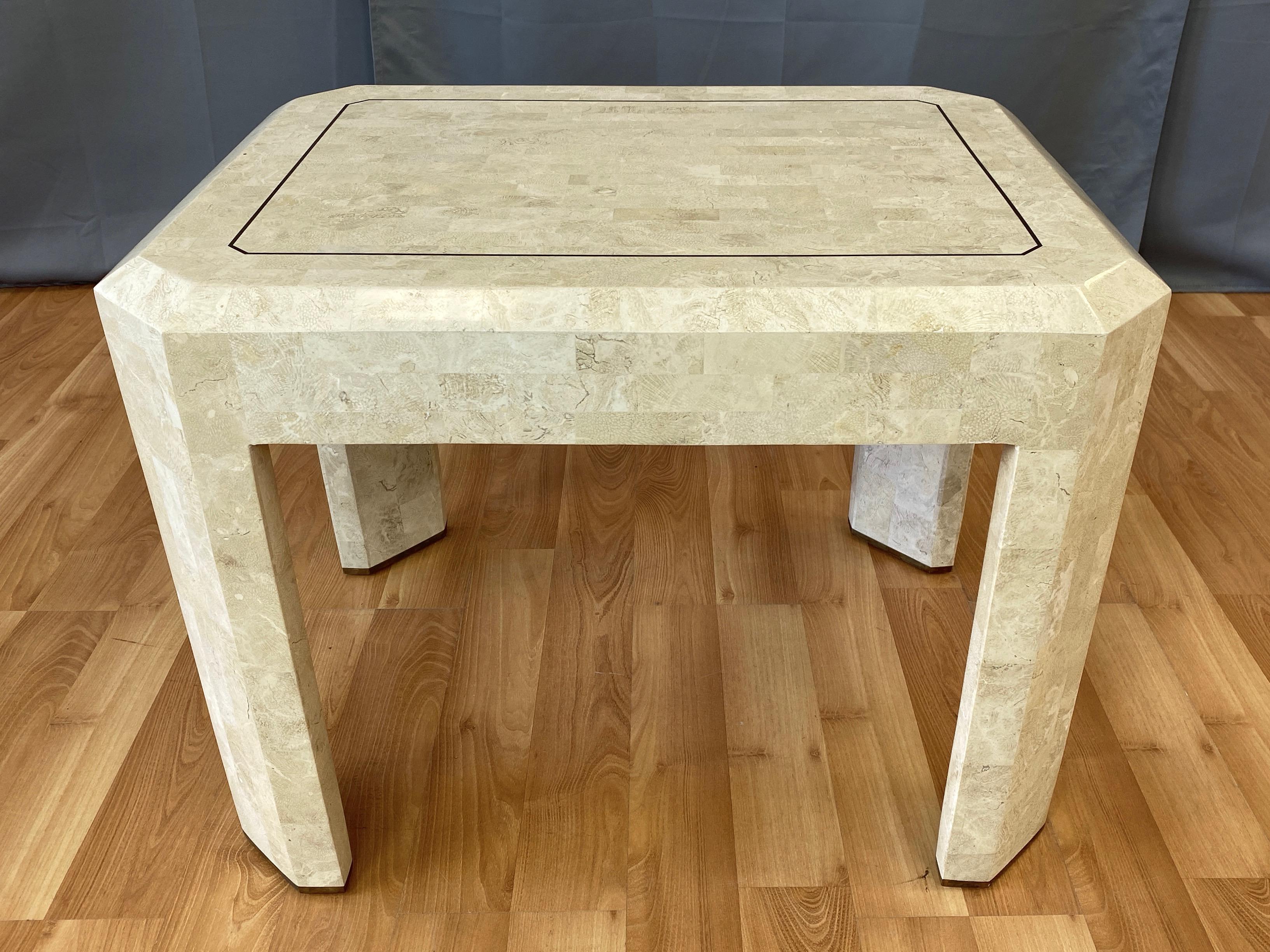 A 1970s tessellated fossil side or cocktail table with brass accents by Maitland-Smith.

Clean rectangular form with wide legs and broadly beveled edges fully finished in smooth, limestone-like fossil tiles. Thin inlayed brass detail on top echoed