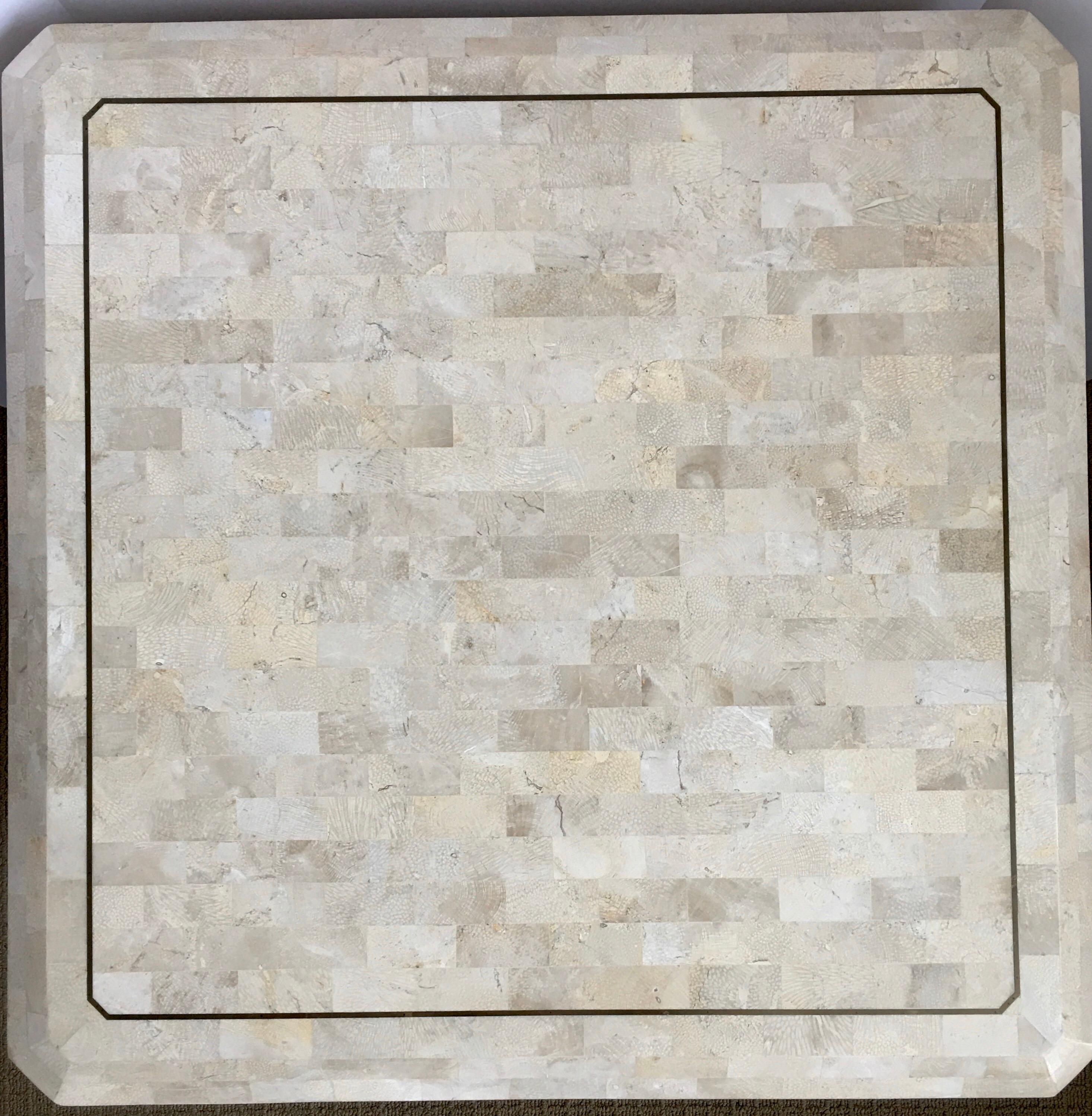 Beautiful Hollywood Regency style tessellated fossil stone marble end table in the style of Karl Springer and Maitland Smith. This occasional wood table features hand-laid neutral cream colored fossil stones with brass inlay trim on top. Overall
