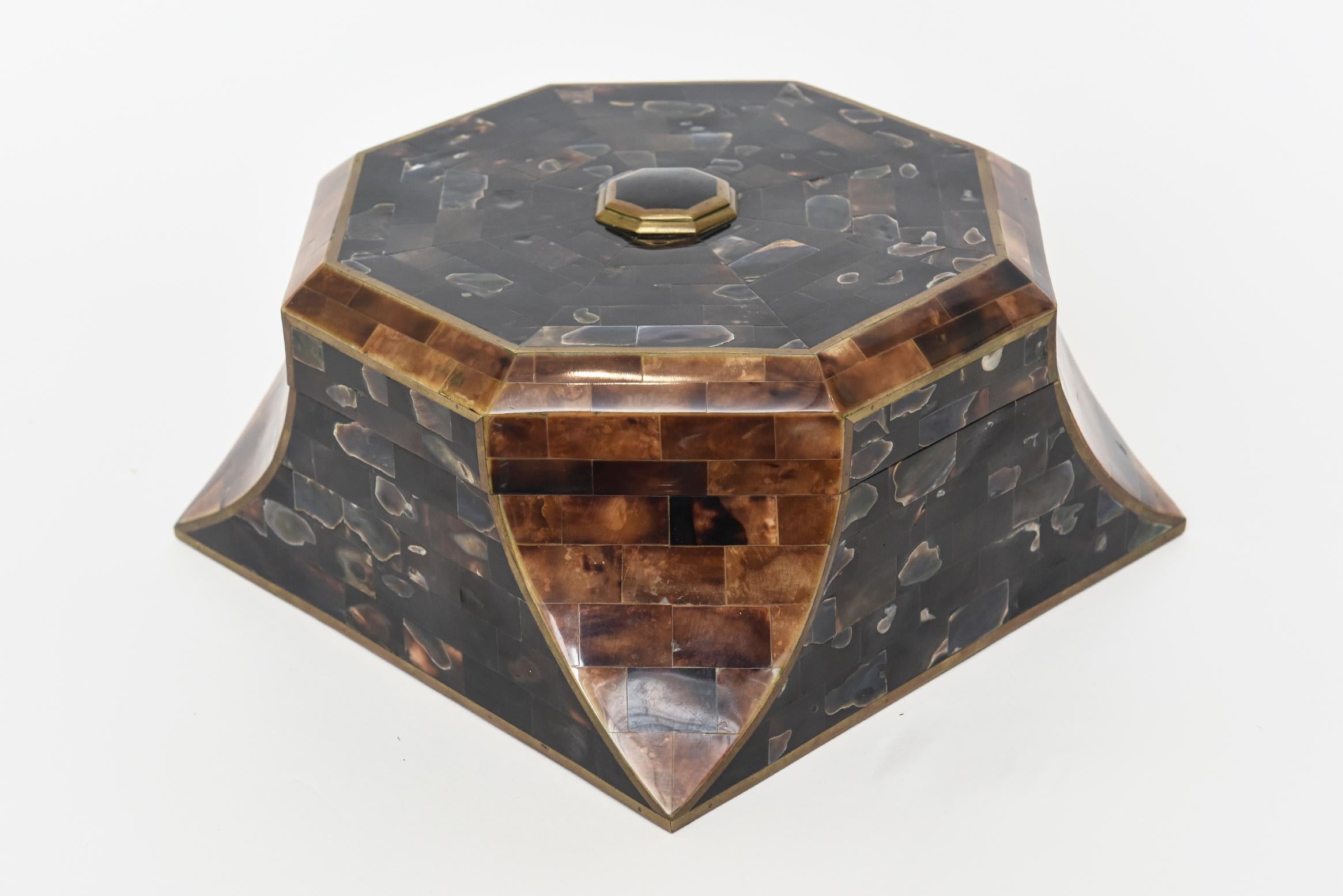 Cette exquise et rare boîte à grande charnière vintage Maitland Smith présente un magnifique médaillon surmonté d'une pierre noire sertie dans du laiton. La boîte est une belle combinaison de corne, d'abalone et d'un intérieur en bois. L'intérieur