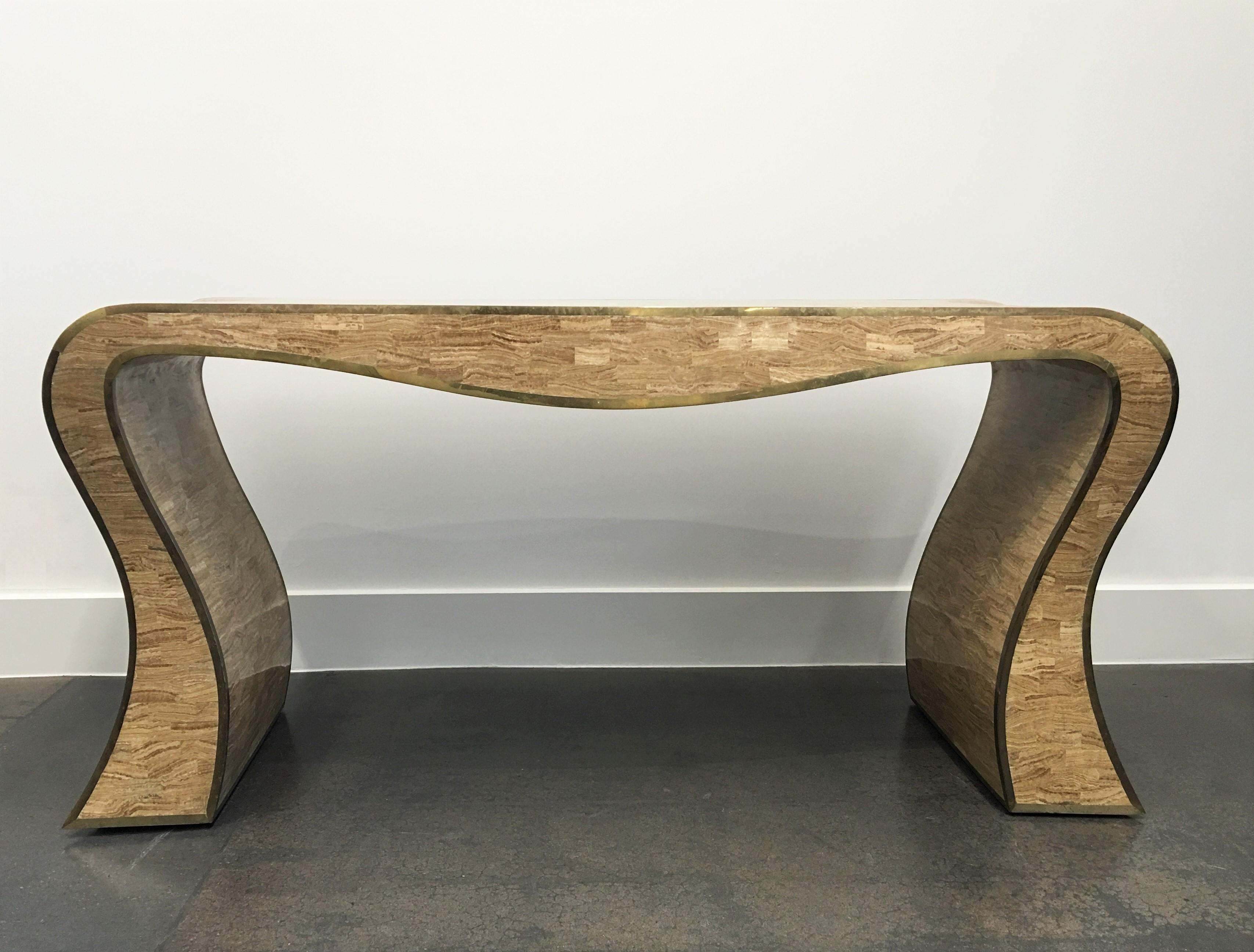 A quite stunning sculptural console table by Maitland-Smith. It is tessellated stone with brass trim in a sinuous form. A very striking table. The brass trimmed is of the finest craftsmanship and has warm patina. Label on the underside.