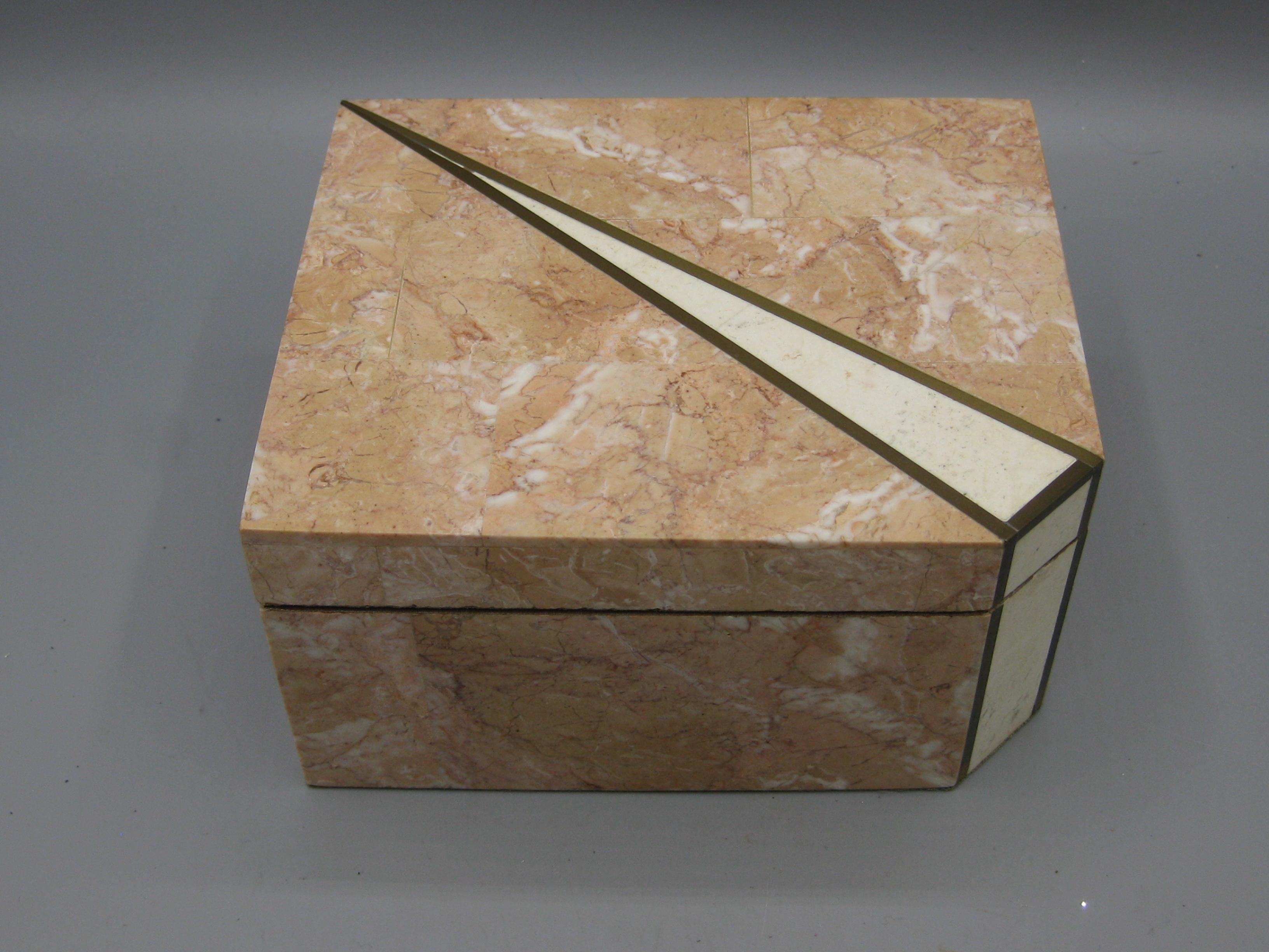 Te ofrecemos una preciosa y elegante caja decorativa con incrustaciones de latón y mosaico de piedra natural teselado, diseñada por Maitland Smith. Esta caja no tiene la etiqueta original en el interior, pero está garantizada que fue diseñada por