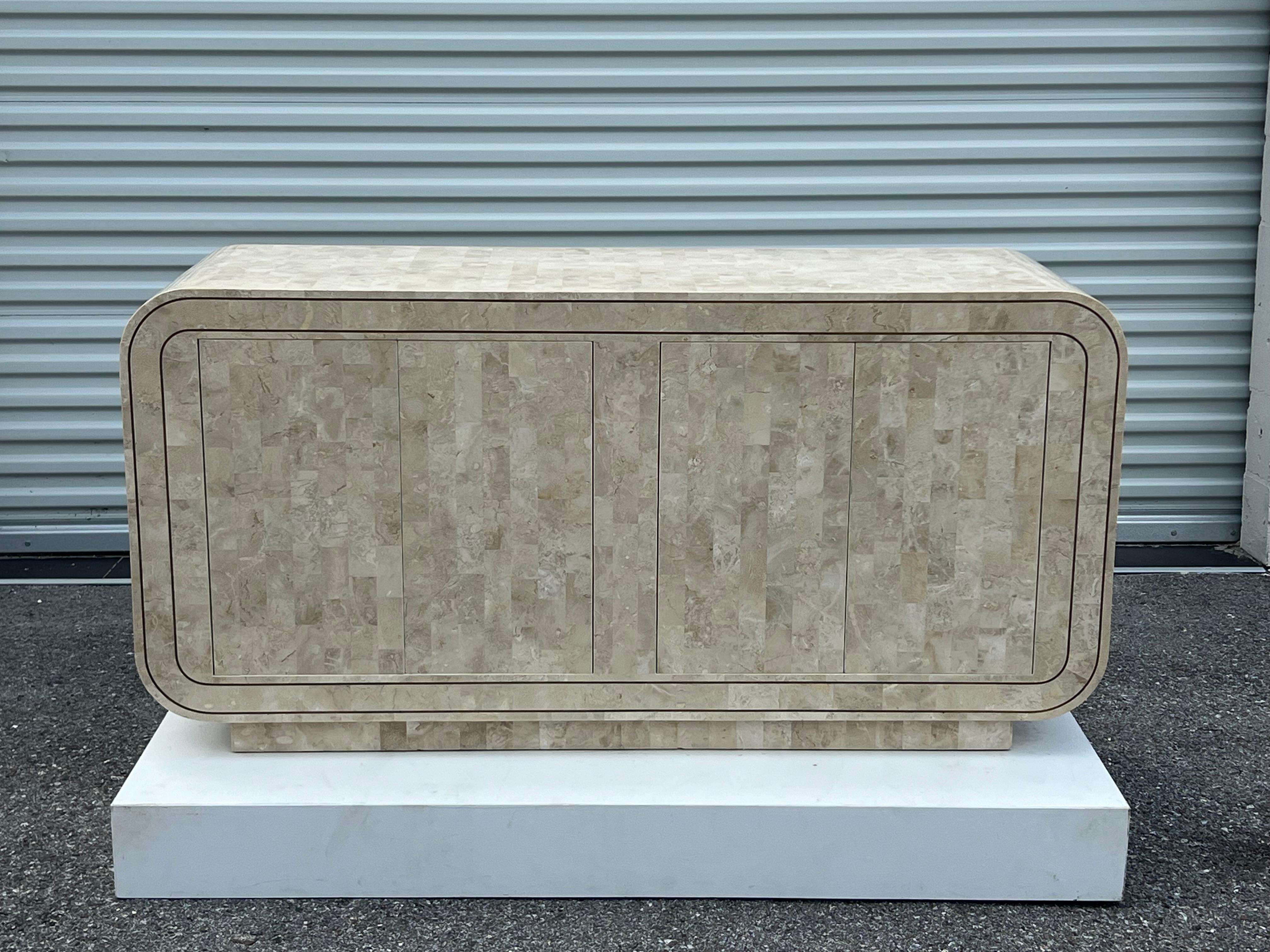 Insolita credenza Maitland Smith con pietra tessellata, bordi arrotondati e intarsi in ottone. Un pezzo sofisticato con una sensazione di lusso e senza tempo. Questo pezzo ha quattro ante e ogni lato ha un ripiano. Porte su cerniere pesanti con