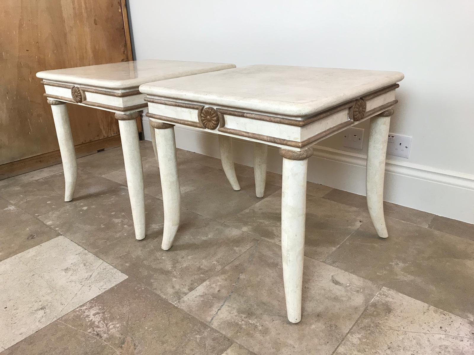 A beautiful pair of ivory colored tessellated stone side tables with light brown contrasting stone detailing and curved legs depicting tusks by the designer Maitland Smith.