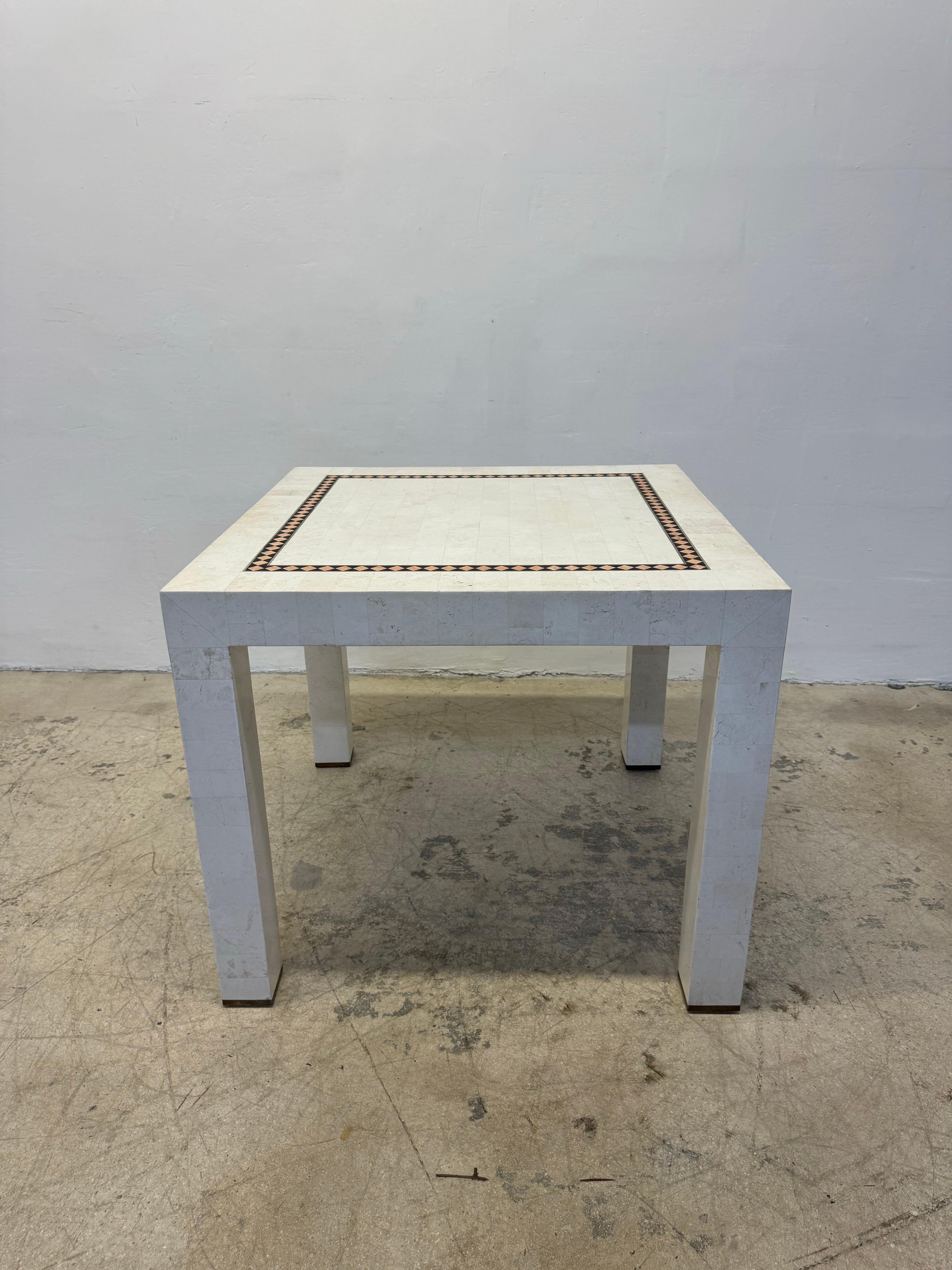 Mid-Century Maitland-Smith game or dining table made with tessellated stone and brass inlay circa 1970s. The tessellated stone is over a wood frame and the legs have brass protector caps.