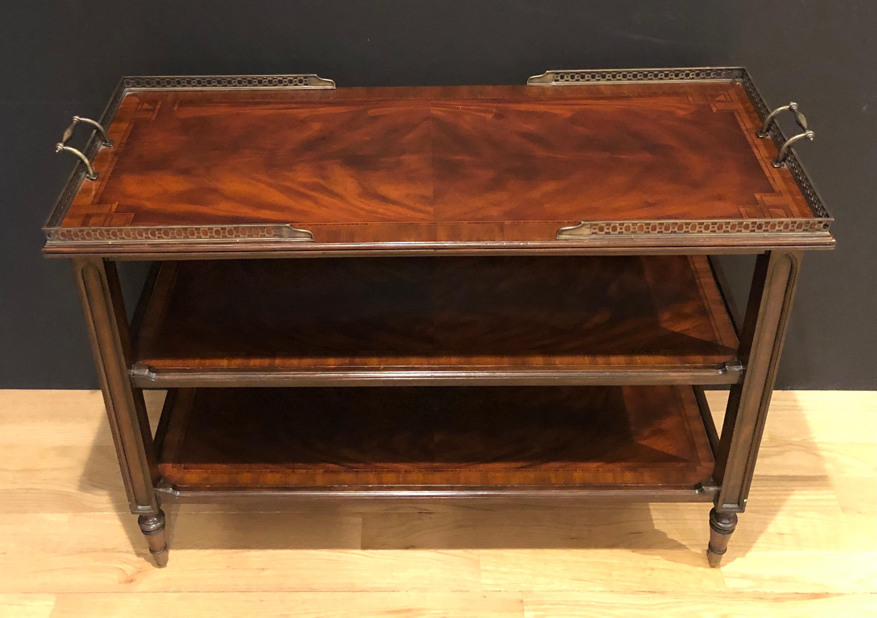 Three-tier brass gallery dessert cart. Beverage trolley or tea cart. Book matched crotch mahogany with boarder inlay and brass pierced gallery. Brass casters and handles on both left and right sides.
Measures: 30