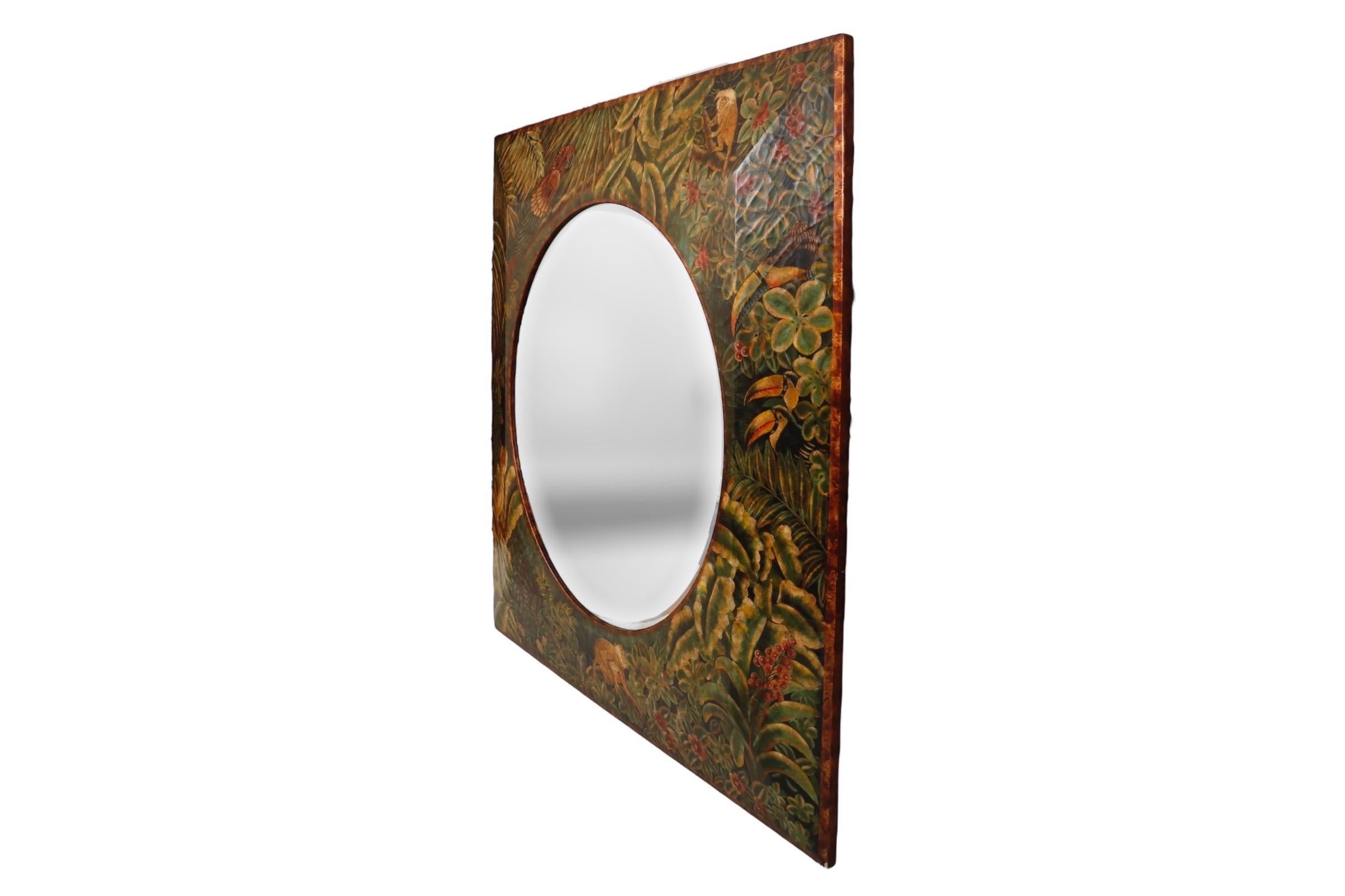 A Maitland Smith tropical wall mirror. A round beveled mirror is set in a square frame with a craquelure finish. Hand painted with lush foliage against a black background, it’s detailed with an abundance of wildlife including a tamarin and patas