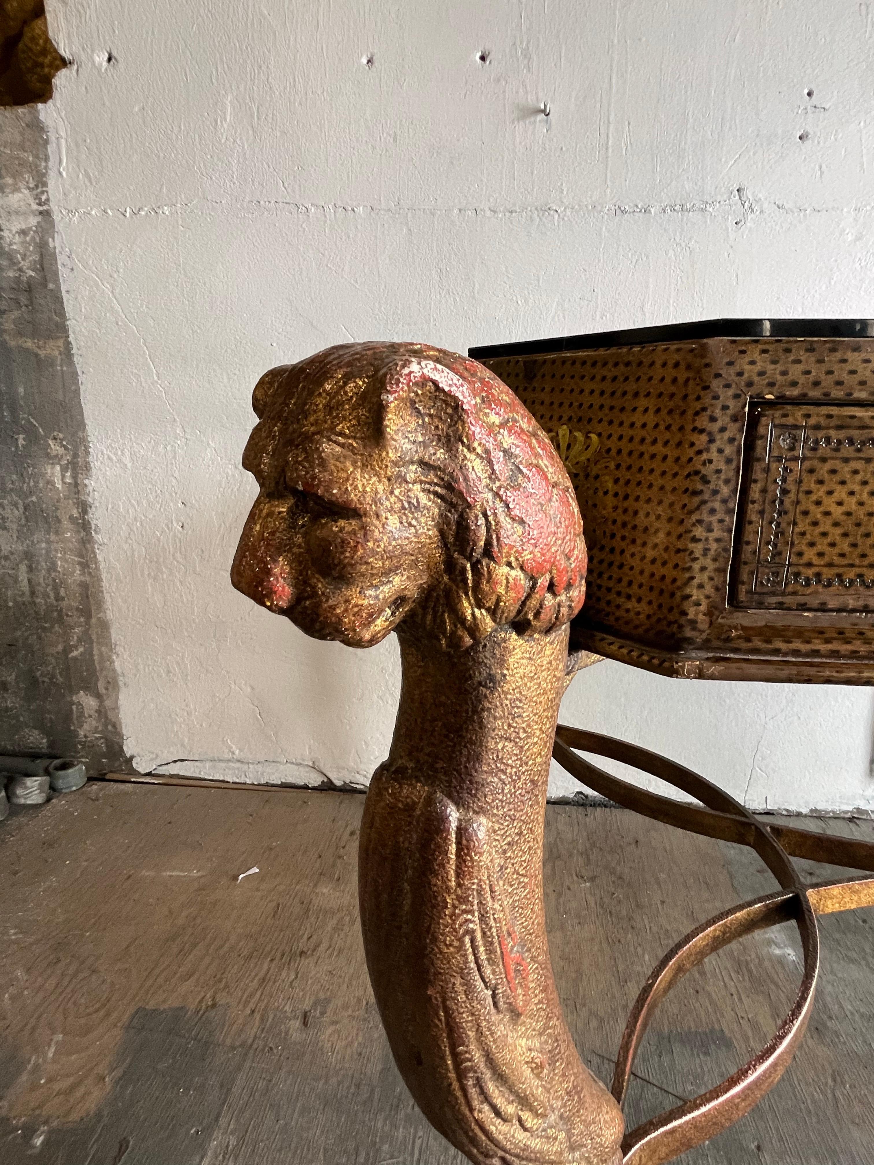 An impressive stylized writing desk by Maitland Smith. Great Egyptian Revival design. Faux Ostrich finish with wonderful iron cat legs. 2 deep shallow drawers with faux leather finish. Smokey glass top. Manufacturer's label in drawer. 