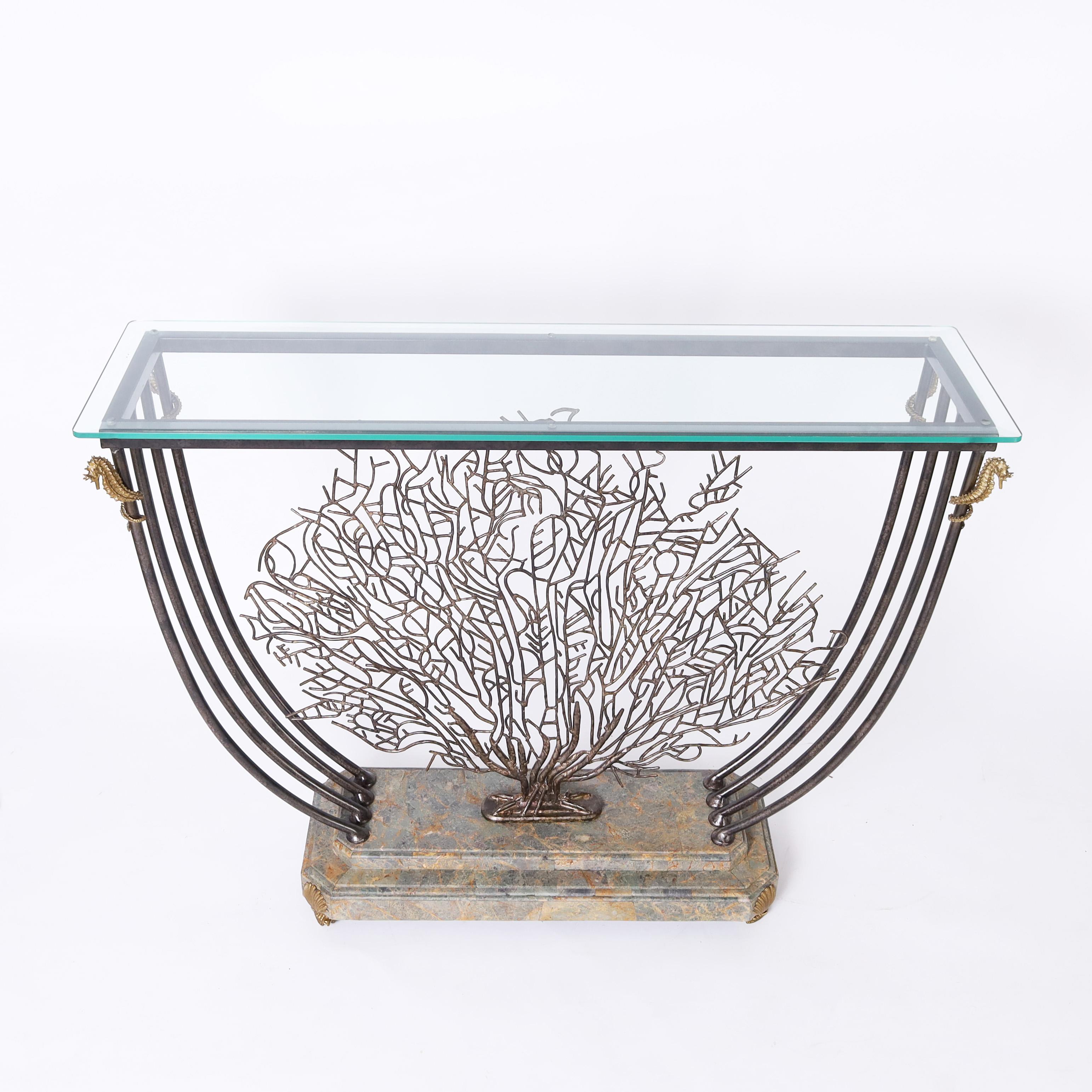 Impressive post modern console table with a beveled glass top with a wrought iron base decorated with gilt bronze sea horses featuring a bronze sea fan on a faux stone base with gilt bronze seashell feet.