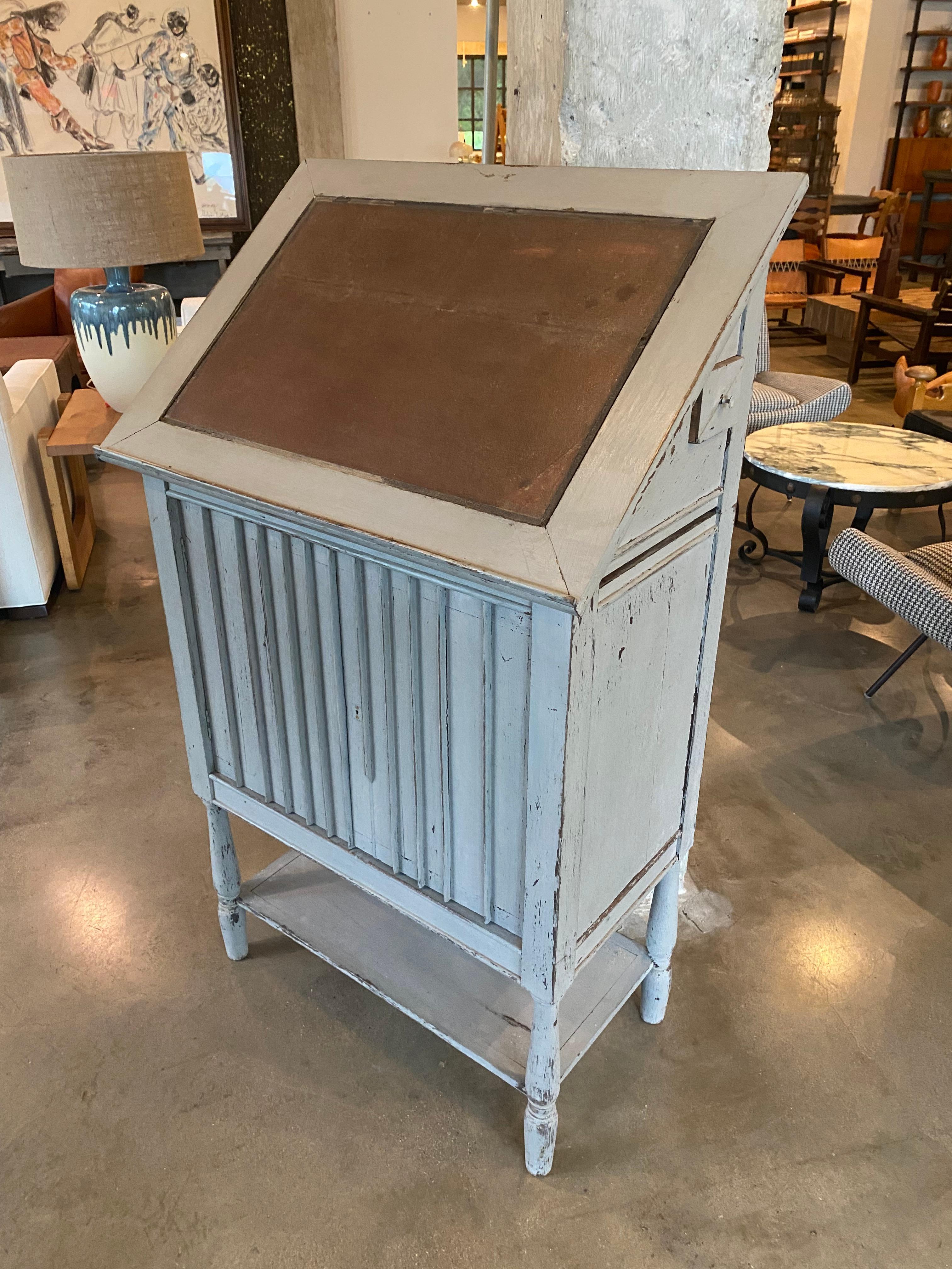 Charming lift top desk or lectern with inset leather buckram desk top, fitted interior, storage, and finished on all sides in light gray paint.  Discreet doors below open to storage.  Would make lovely music stand, secretary, or restaurant Maitre d'