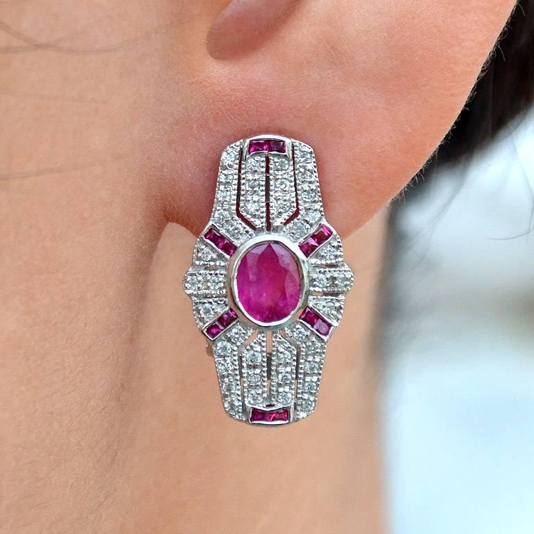 Pair of Art Deco design with ruby and diamond earrings, each of shield-shaped, millegrain set with round diamonds and French cut ruby surround the natural oval ruby.  

Information
Metal: 18K White Gold
Width: 12 mm.
Length: 22 mm.
Weight: 8.28 g.