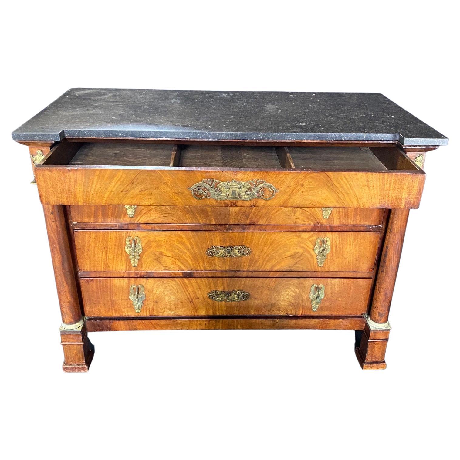 Found in the South of France, this exquisite burled walnut commode from the early 19th century features a dark grey marble top over four drawers. The lower three drawers are recessed and flanked by elegant columns with bronze Doric capitals and
