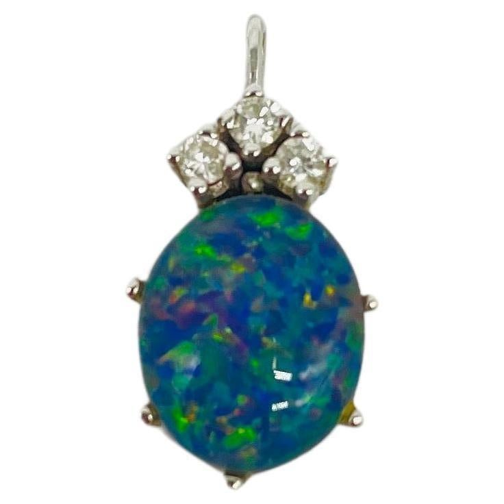 Immerse yourself in the dreamlike beauty of this exquisite 14k white gold pendant, a true work of art that captivates with its elegance and grace. The centerpiece of this pendant is a stunning oval-shaped opal, exuding iridescence and charm.