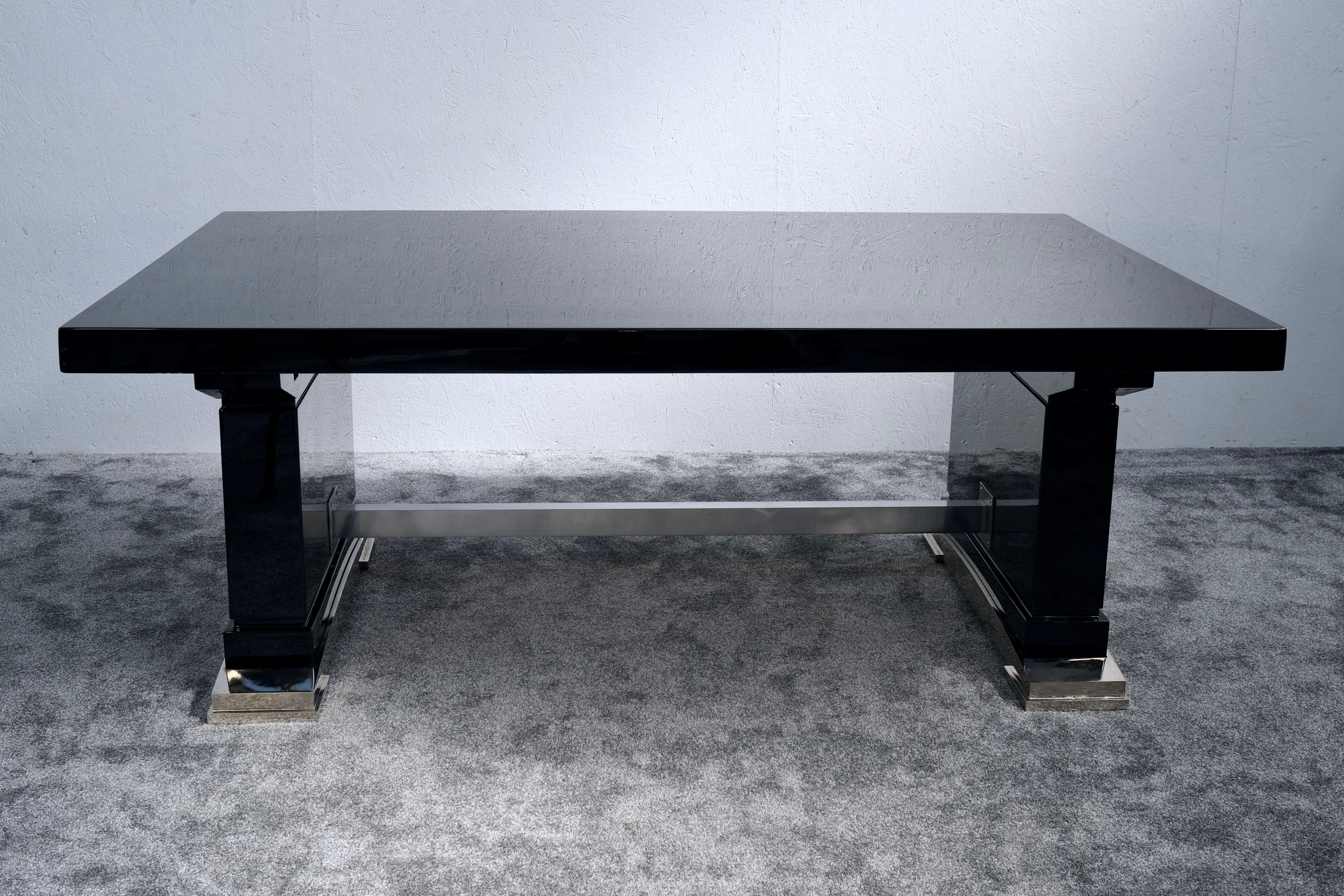 Une pièce maîtresse qui allie la force de l'architecture à l'élégance française :
Cette impressionnante table de salle à manger Art déco est revêtue d'une laque piano d'un noir profond et met en valeur les lignes nettes et symétriques