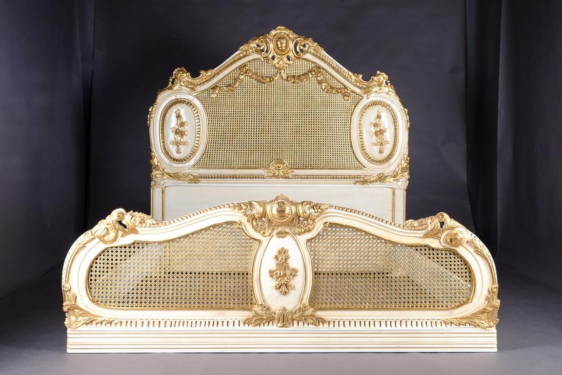 Majestuosa cama barroca de estilo Luis XVI.

Madera maciza de haya, finamente tallada, coloreada y dorada. Pie bajo y cabecero alto, doble trenzado, armazón del respaldo curvado. Coronación de rocaille calada.

La dimensión interior del colchón