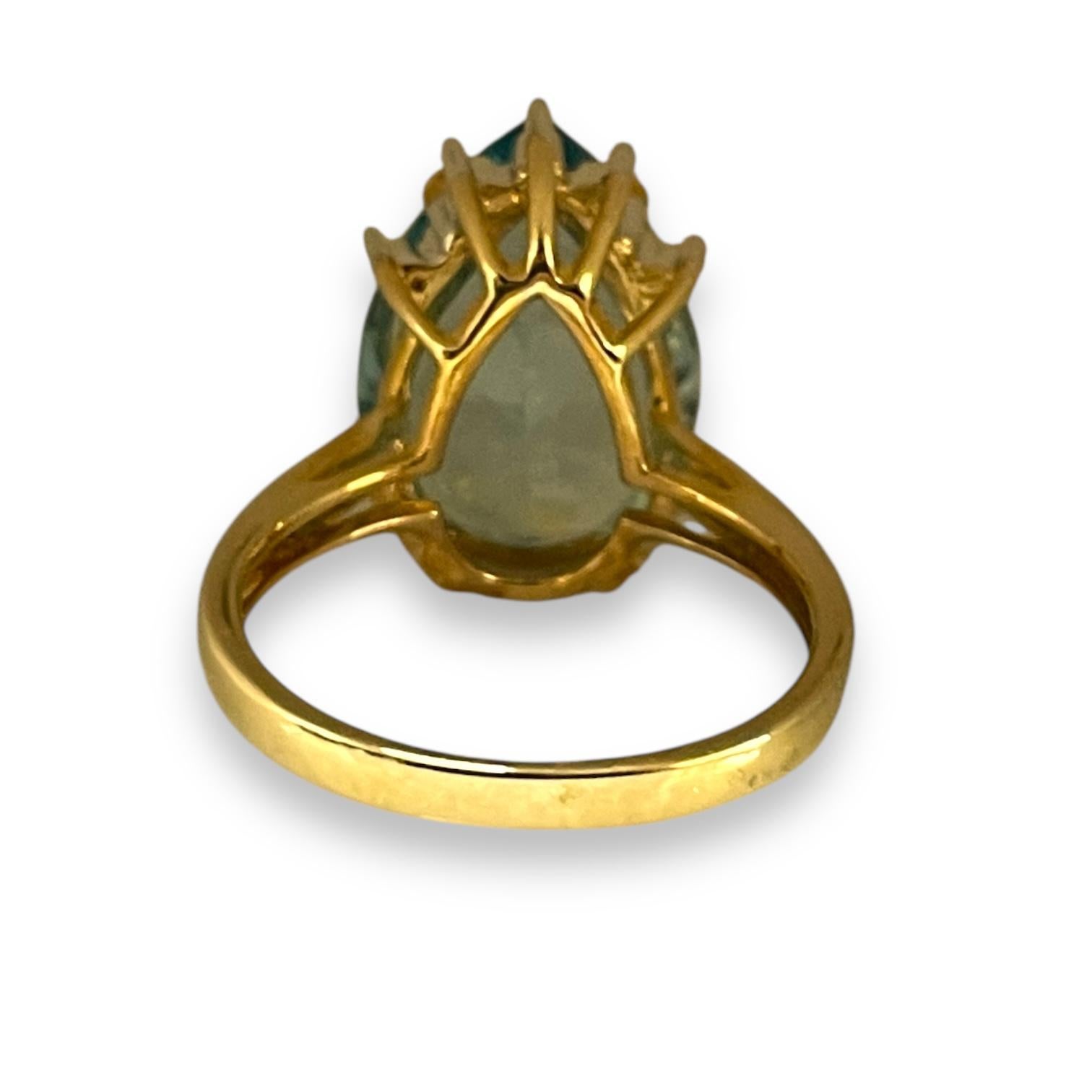 This stunning blue topaz teardrop ring features a luminous blue stone set in elegant yellow gold, accented by finely crafted prongs that gracefully cradle the gemstone. The eye-catching, shimmering topaz exudes a deep oceanic hue, radiating