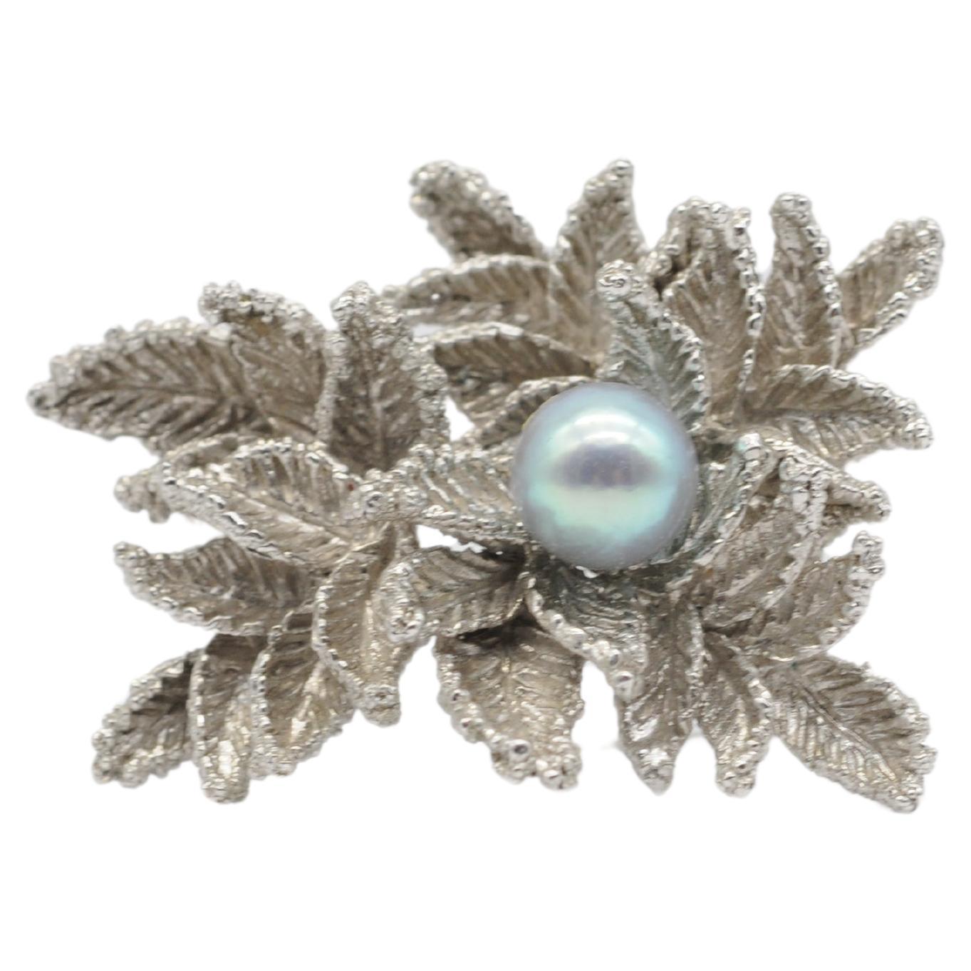 Immerse yourself in the enchanting beauty of this stunning 14k white gold brooch, designed in a captivating leaf-like motif that conceals within its folds a magnificent dark Tahitian pearl. This charming piece exudes an irresistible allure,