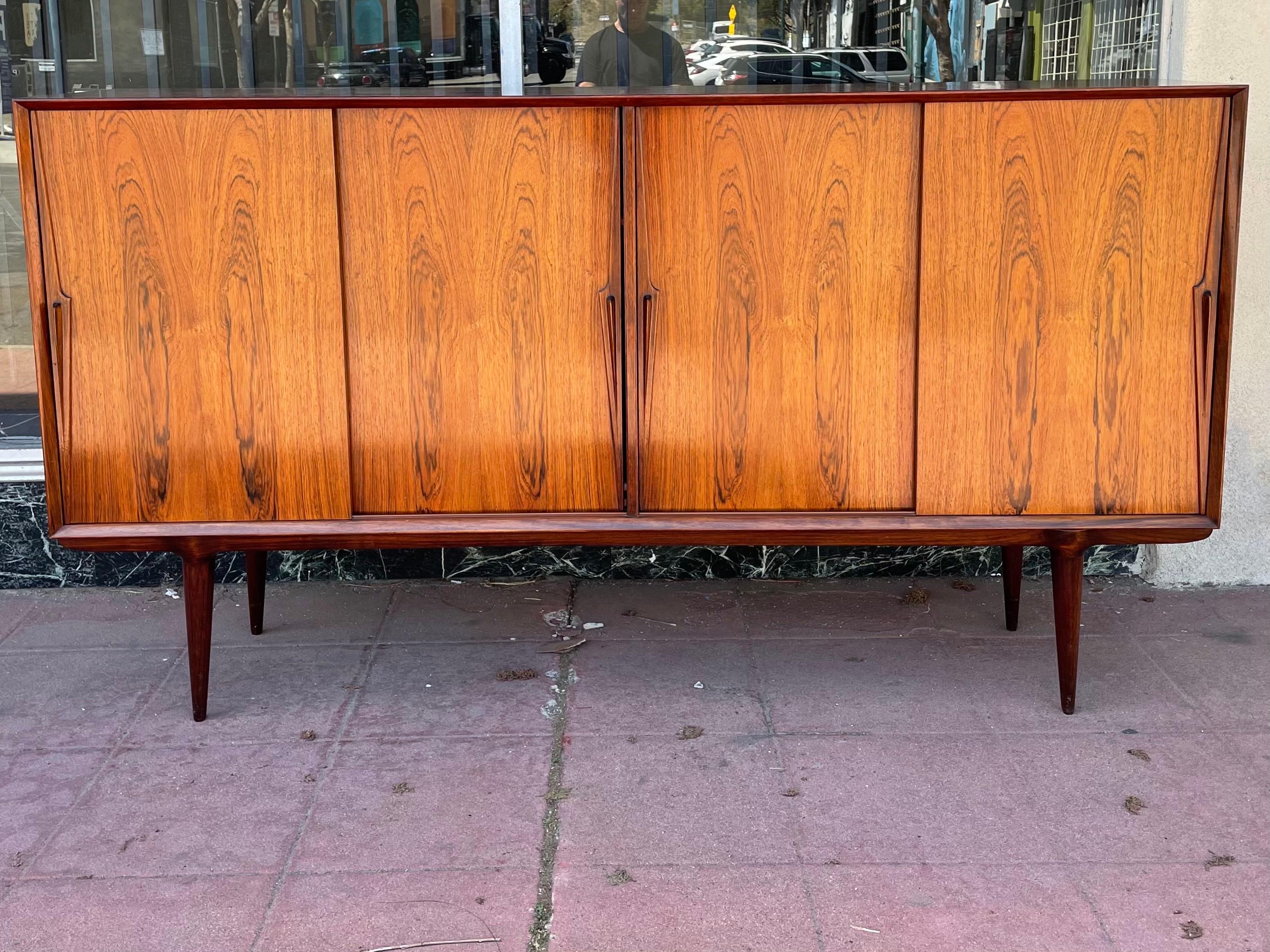 Beautiful Gunni Omann Palisander sideboard from the 1950s.

Designed for Omann Jun Møbelfabrik in the mid-20th century, this piece is an extremely well preserved example of Mid-Century Danish Furniture.

The front is composed by four sliding