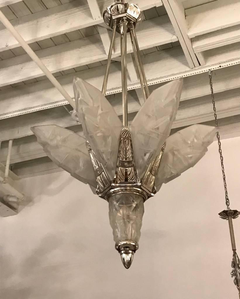 French Art Deco chandelier signed by Degue. Having six overflowing geometric clear frosted glass panels and one matching center glass shade. Held by matching geometric nickel-plated design frame. Has been re plated in polished nickel and re wired