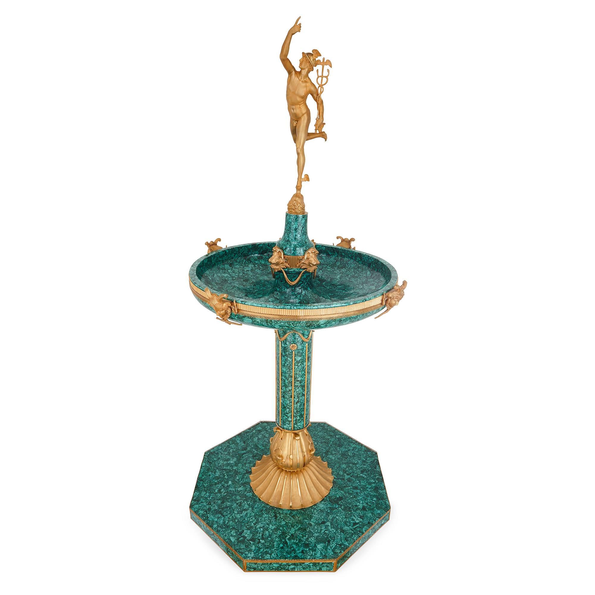 This Italian fountain showcases extremely skilled design and craftsmanship, with Classical detailing all-over. It dates to the late 19th century, with later malachite veneer. The fountain is mounted at the top with a gilt bronze statue of the Roman