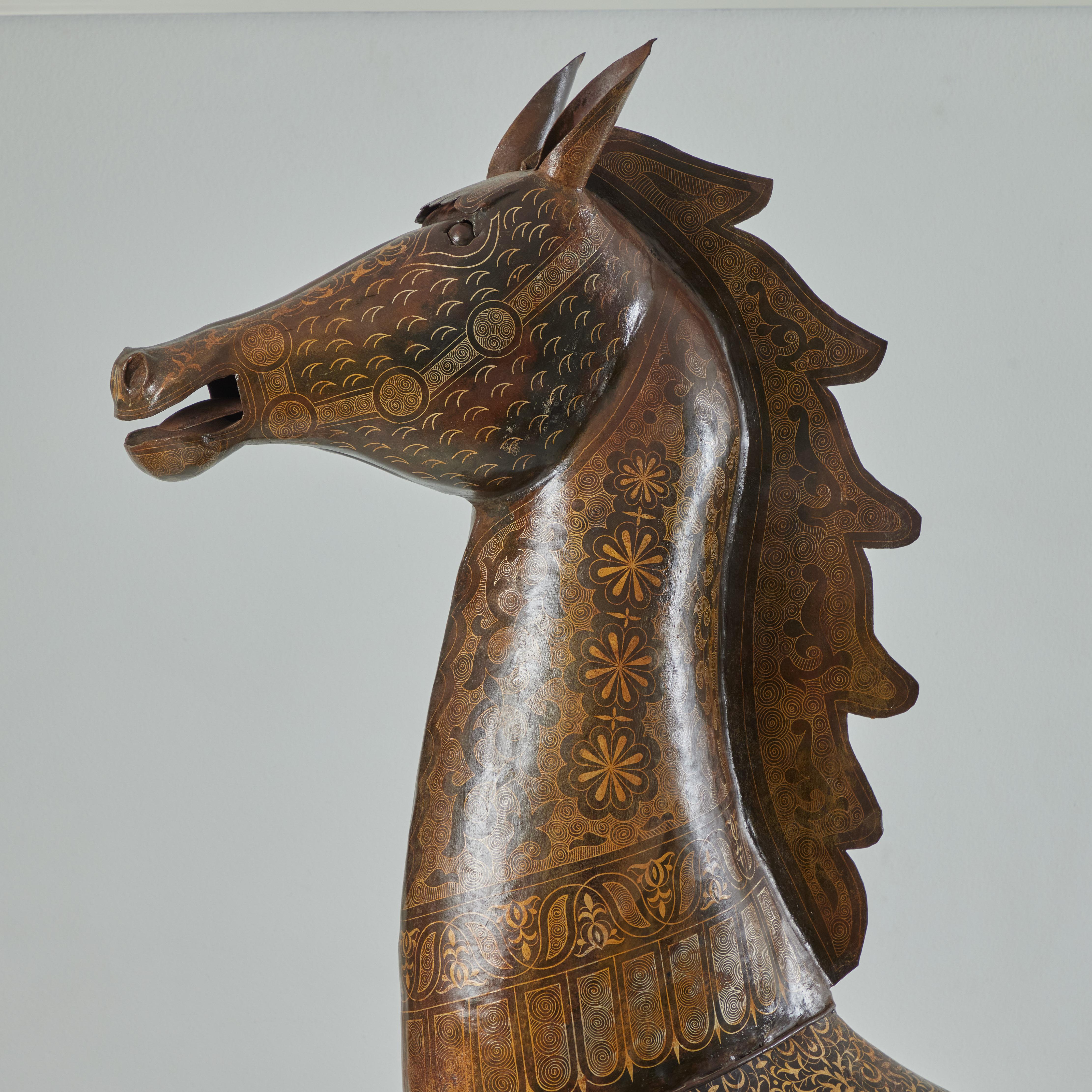 This is a majestic life size metal horse with hand embellishment. The head and the legs are welded on to the body. Standing steadily and tall, the horse has been hand embellished with gold that has been embedded in the metal. An intricate design